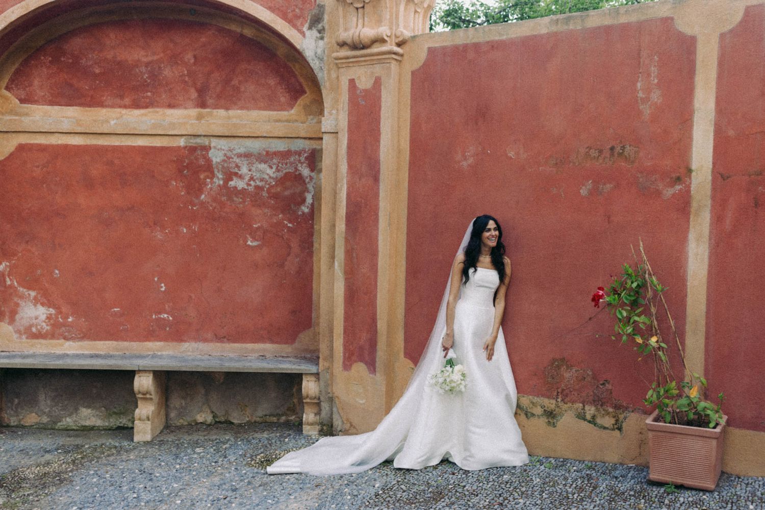 A series of five connected photos showing a person in a white wedding dress posing against a rustic red wall.