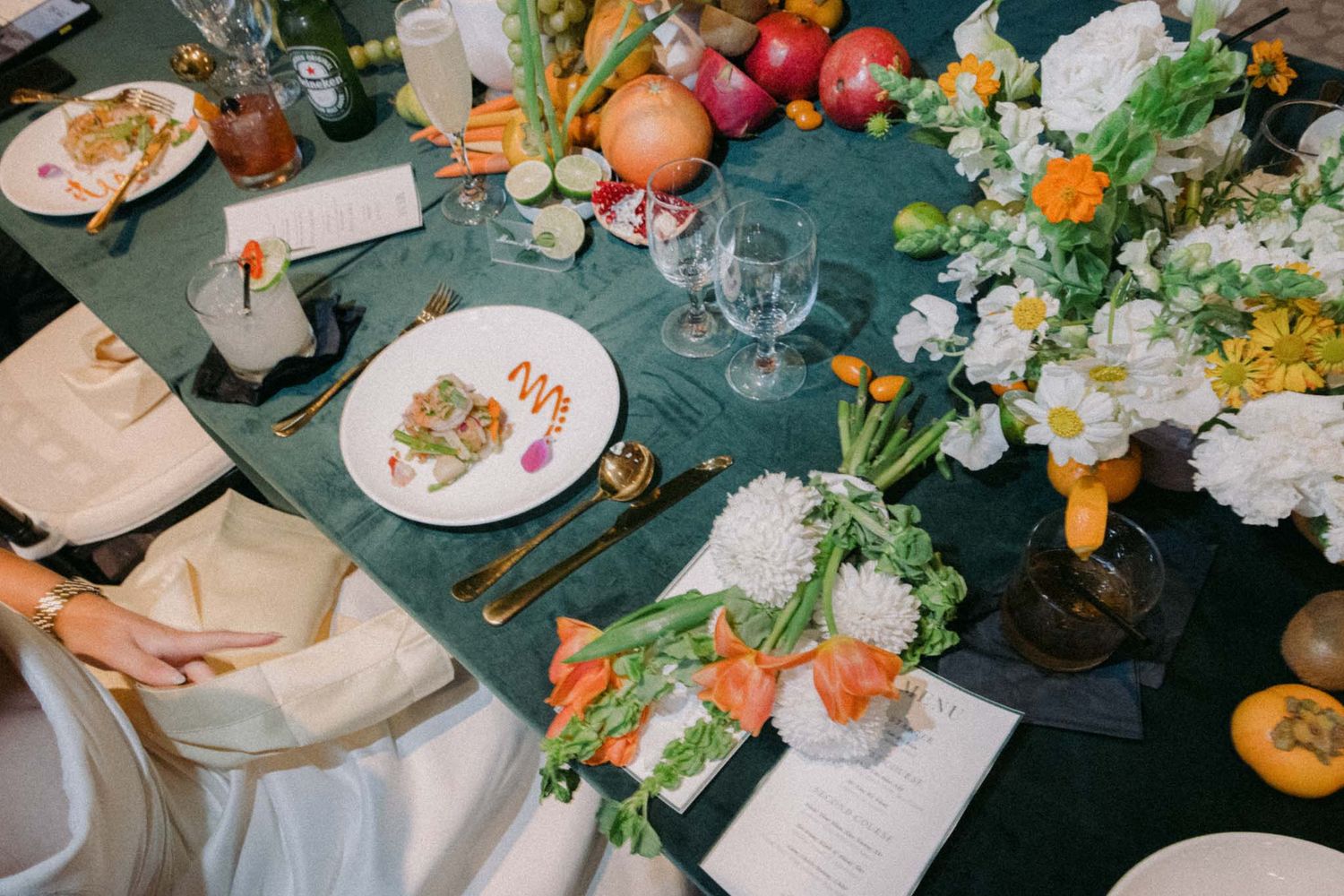 An elegant dinner table setting with fresh flowers, plates, and glassware arranged on a dark tablecloth.
