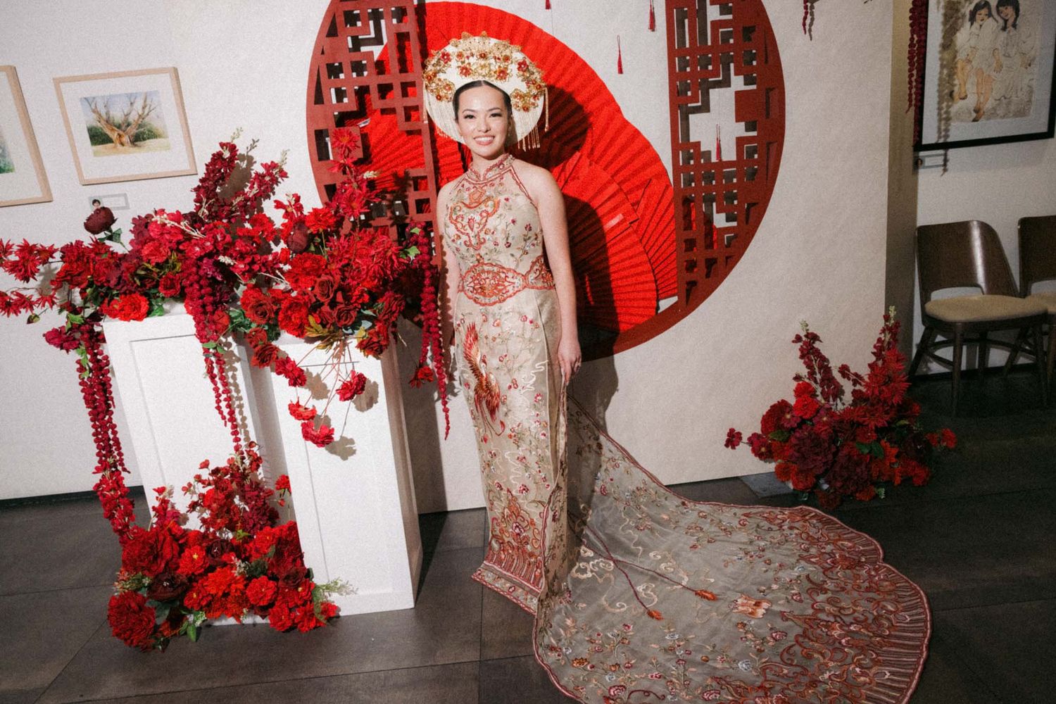 Traditional Chinese wedding decor features vibrant red paper umbrellas and cherry blossoms against white walls.