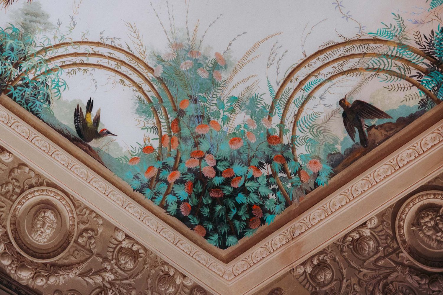 Ornate ceiling details with floral motifs and painted vines create an elegant architectural pattern in a historic interior.
