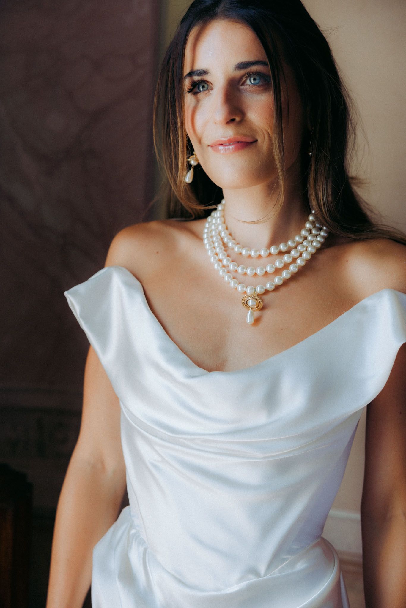 A series of close-up shots showing a white satin dress with cowl neckline and pearl necklace details.