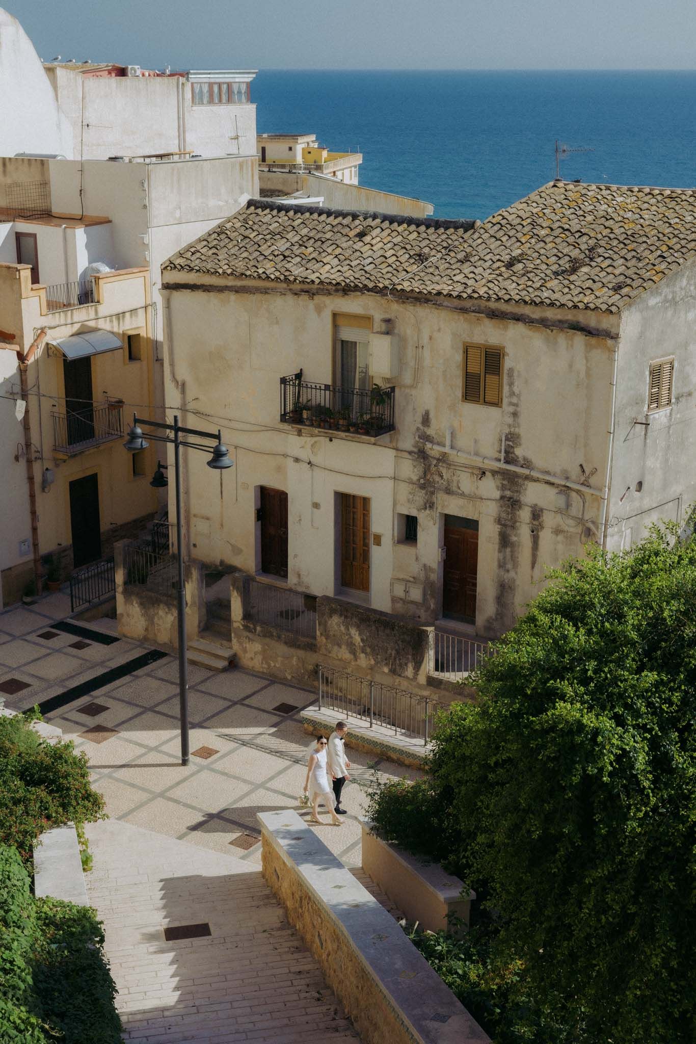 Aerial view of a Mediterranean coastal town with white buildings and narrow streets overlooking the blue sea.