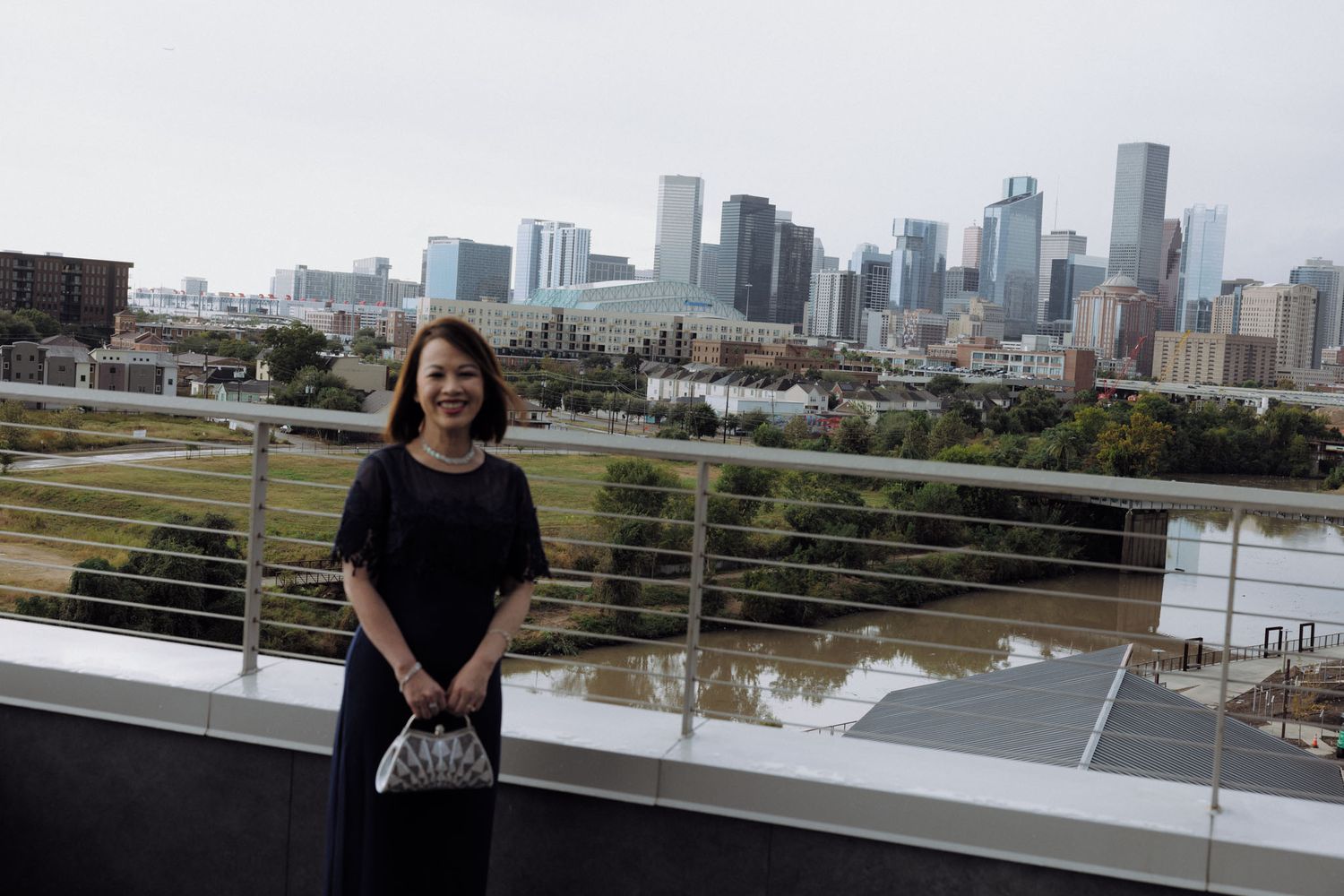 A scenic view of the Houston skyline with tall buildings reflecting in Buffalo Bayou from a waterfront observation deck.