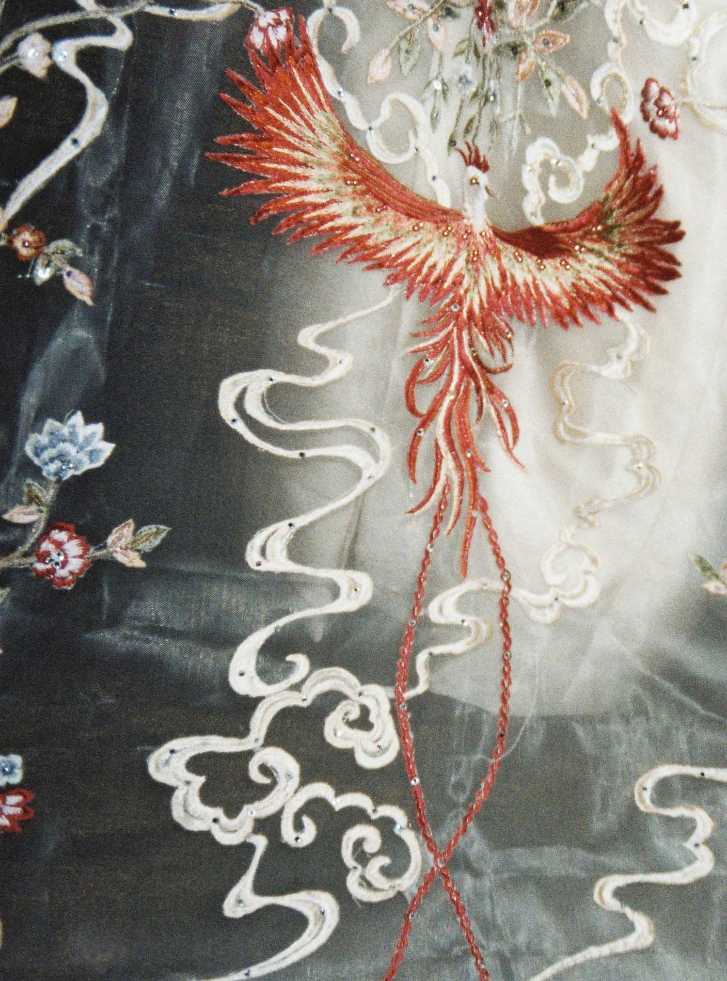 A traditional Asian painting depicts a majestic red phoenix soaring through swirling clouds against a dark background.