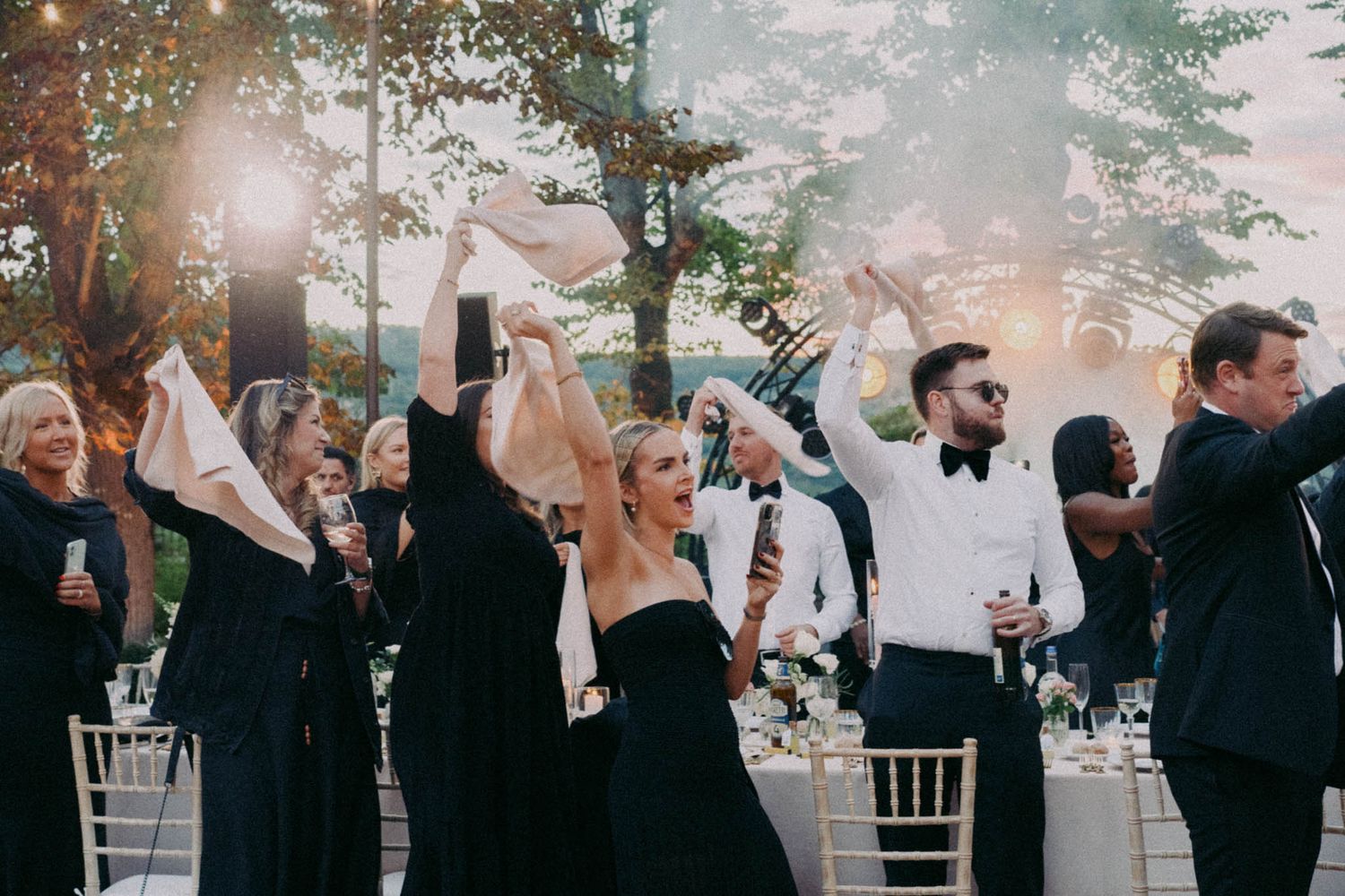 A series of candid wedding celebration moments captured in black and white showing guests dancing and celebrating.