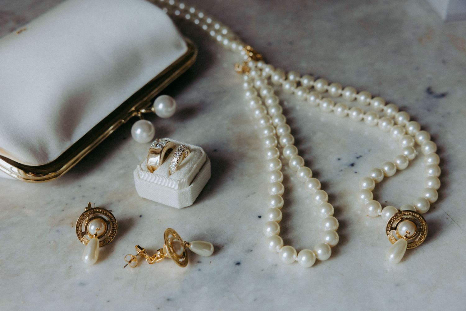 Delicate pearl necklaces and vintage jewelry pieces arranged artistically on a textured gray surface.