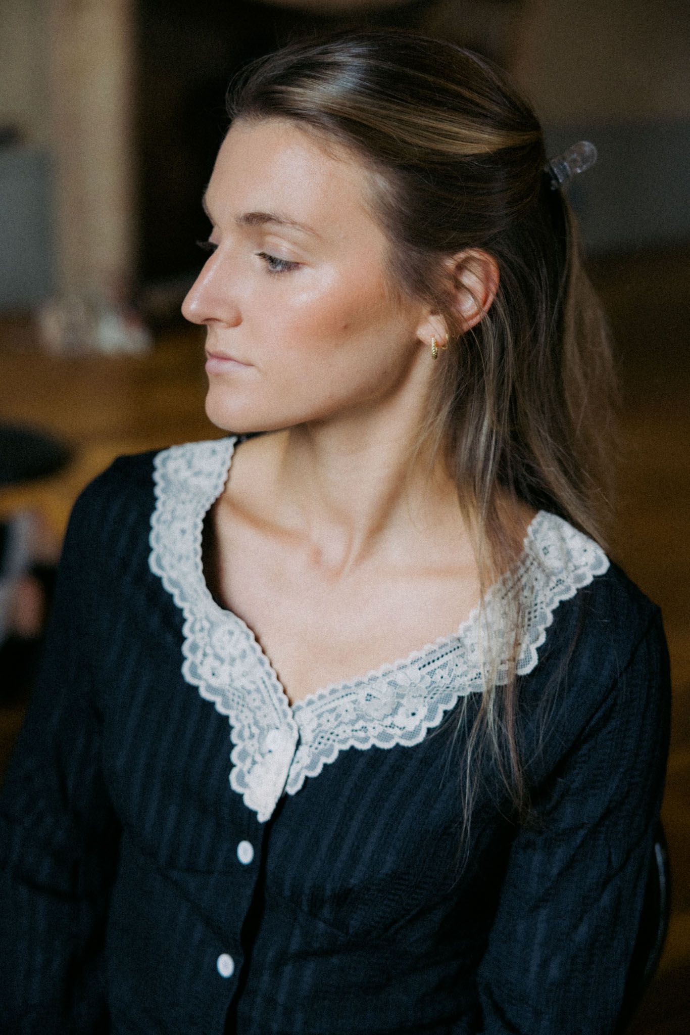 A person in a black dress with white lace collar shown in a series of side profile poses.