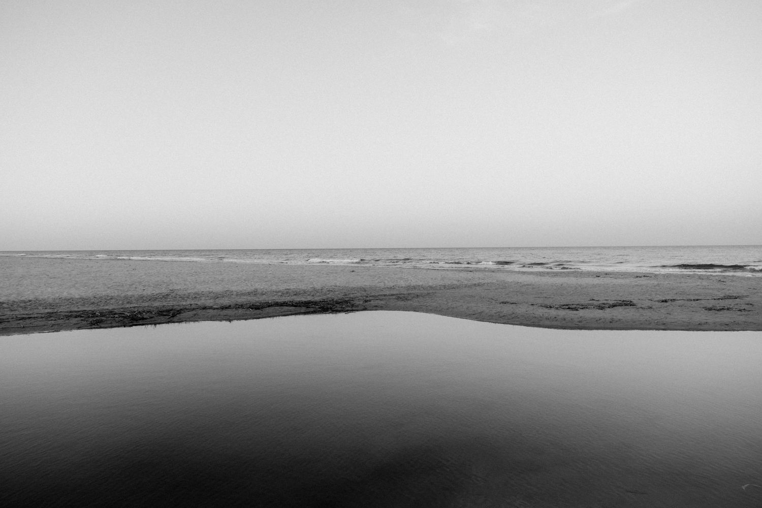Minimalist black and white landscape showing a misty coastal horizon over water.