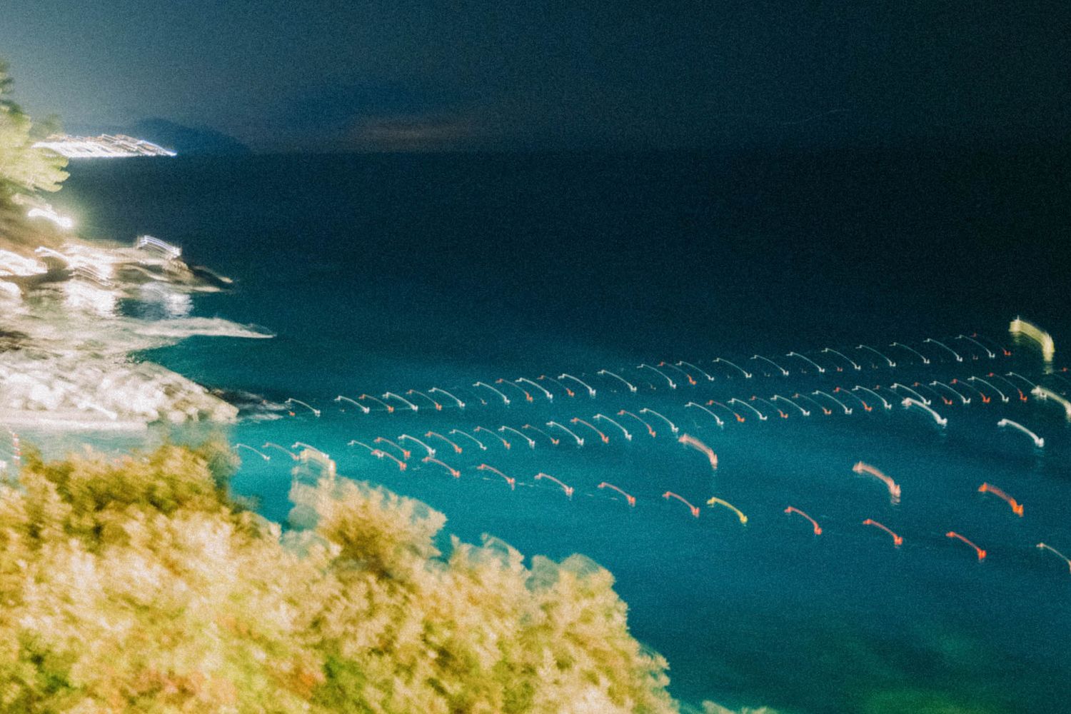 Aerial view of parasails floating above turquoise waters near a coastal cliff.