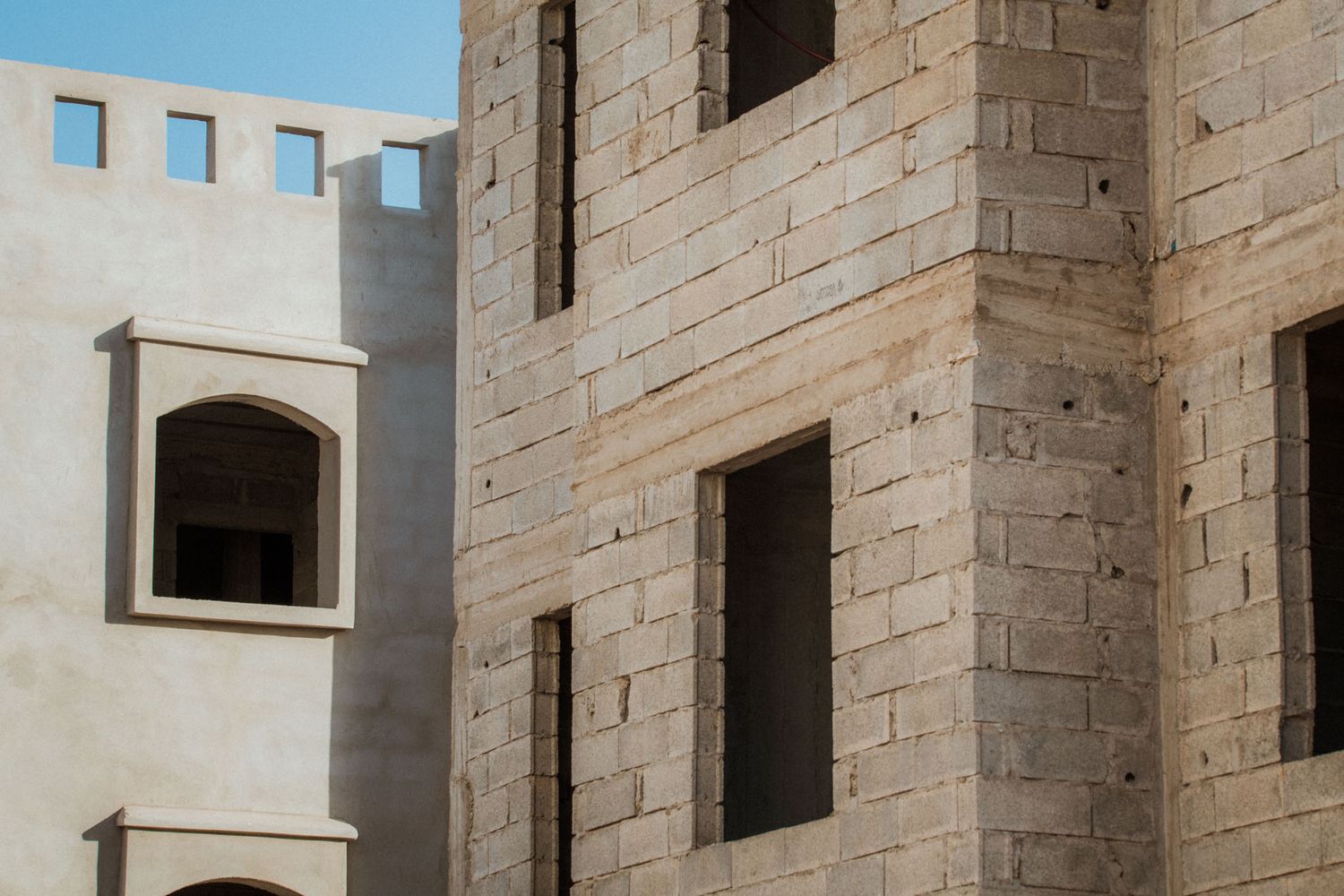 Stone walls and arched windows of a historic building with beige limestone architecture in Mediterranean style.