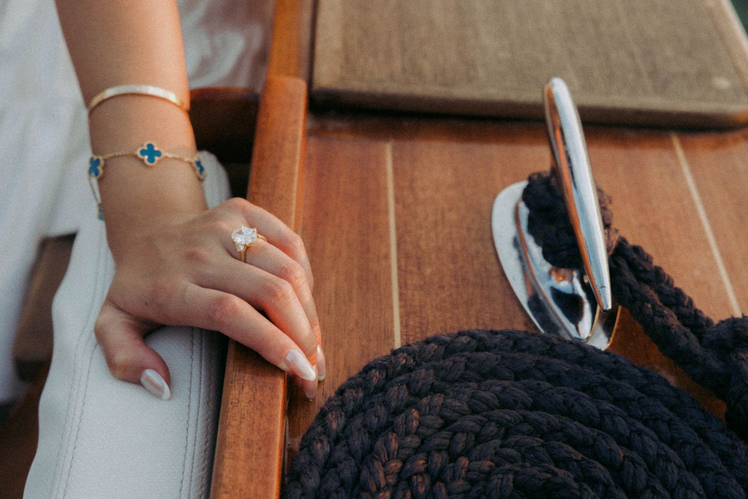 Close-up of hands crocheting with black yarn and a silver hook on a wooden surface.