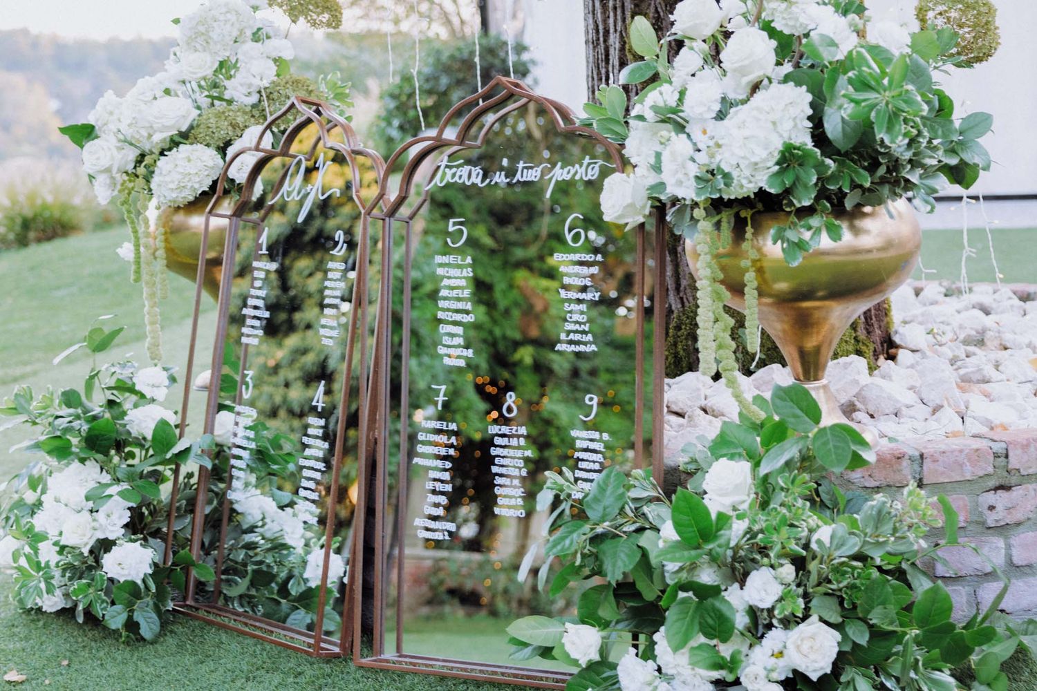 Rustic wooden arch decorated with cascading white flowers and greenery for an outdoor garden wedding ceremony.