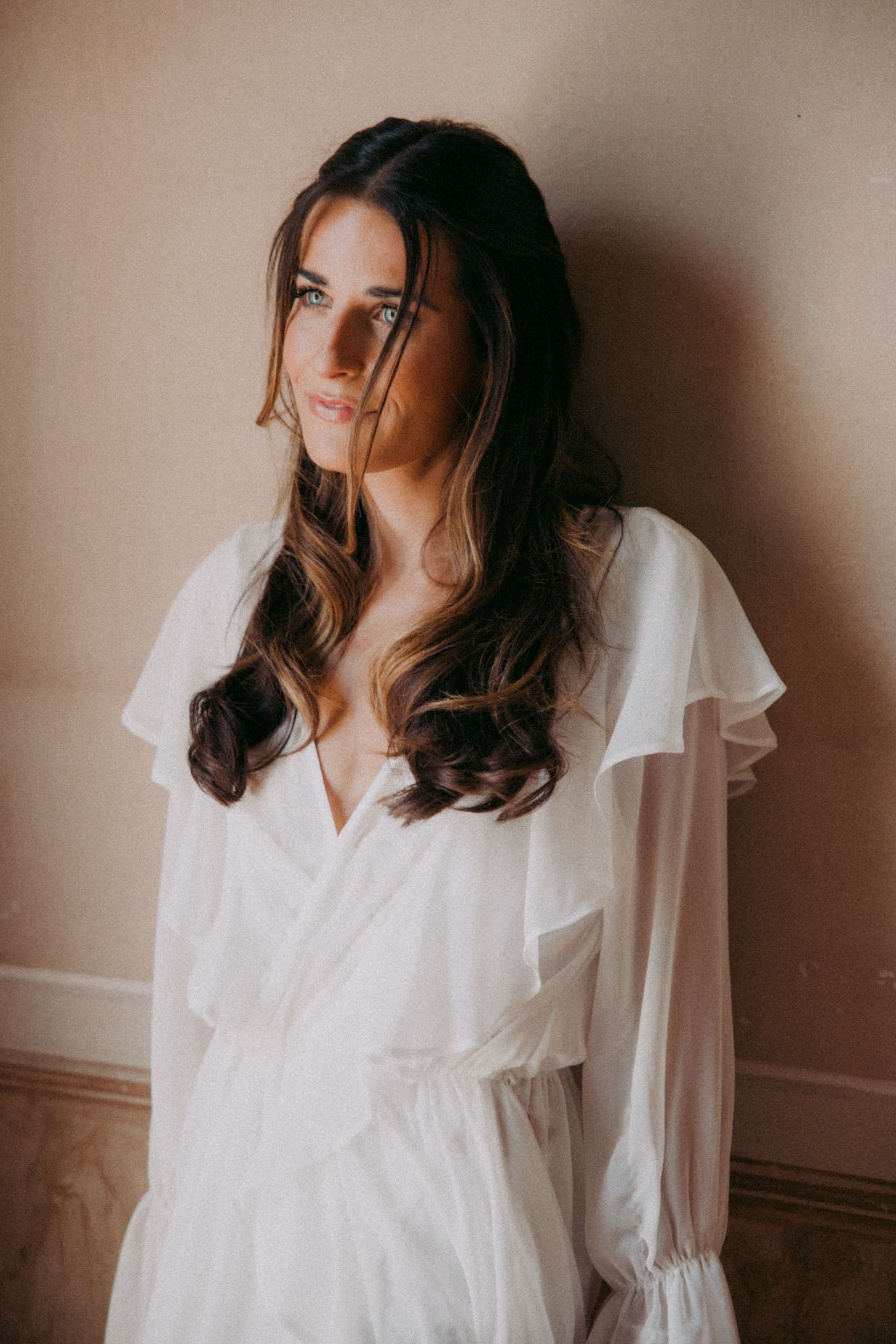 Artistic portrait series in warm tones showing a woman in a flowing white dress against a neutral wall.