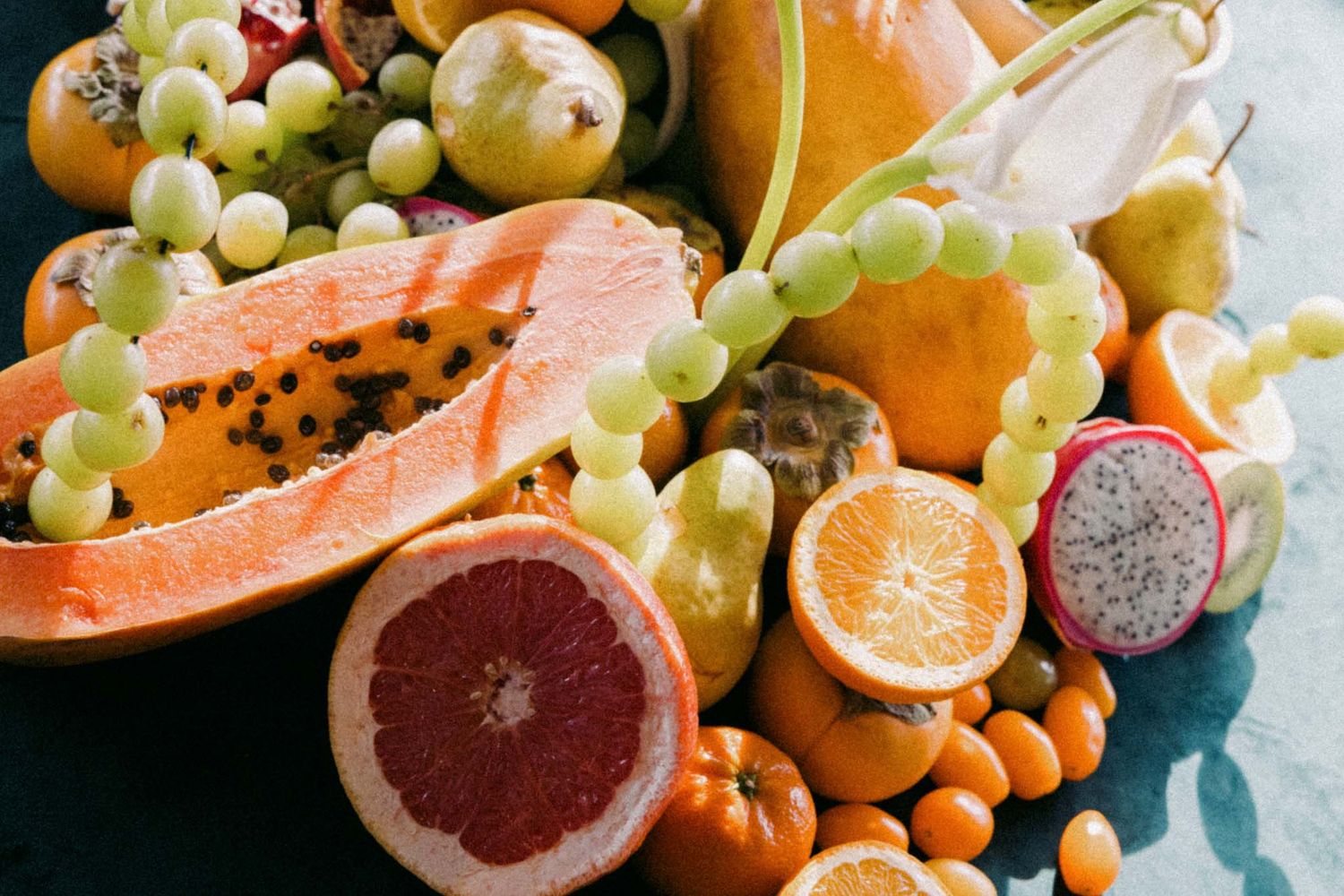 Fresh citrus fruits, grapes, and nuts arranged on a rustic wooden surface in a vibrant display of healthy ingredients.
