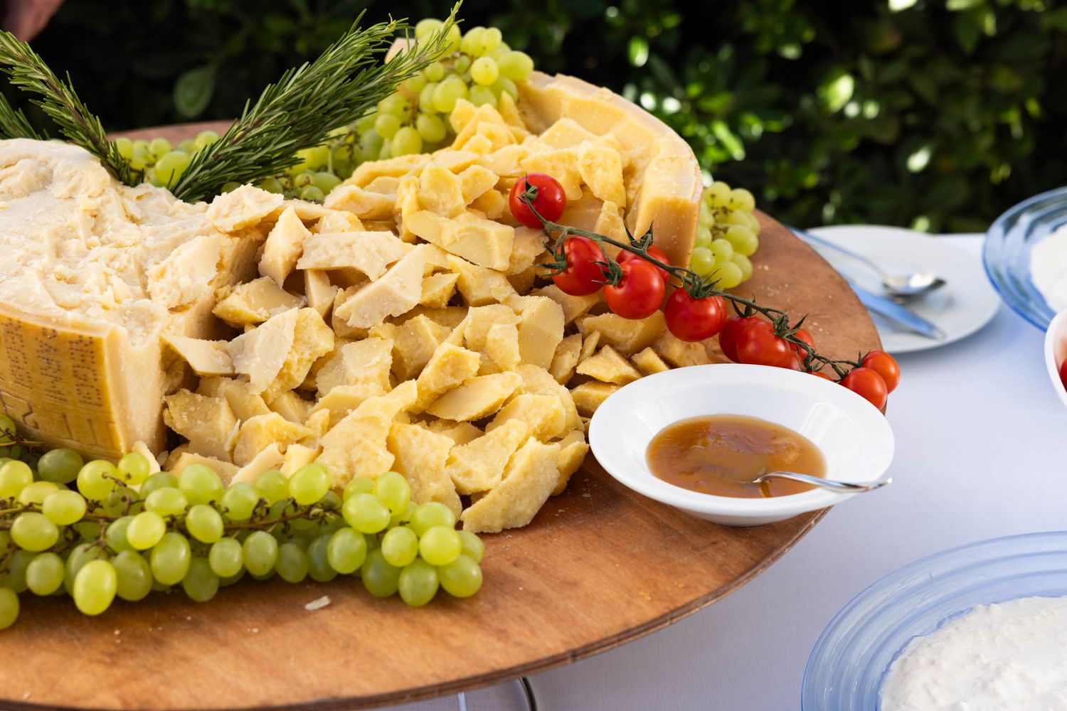 A charcuterie board with grapes, cheese, meats and dipping sauces arranged on a rustic wooden surface.