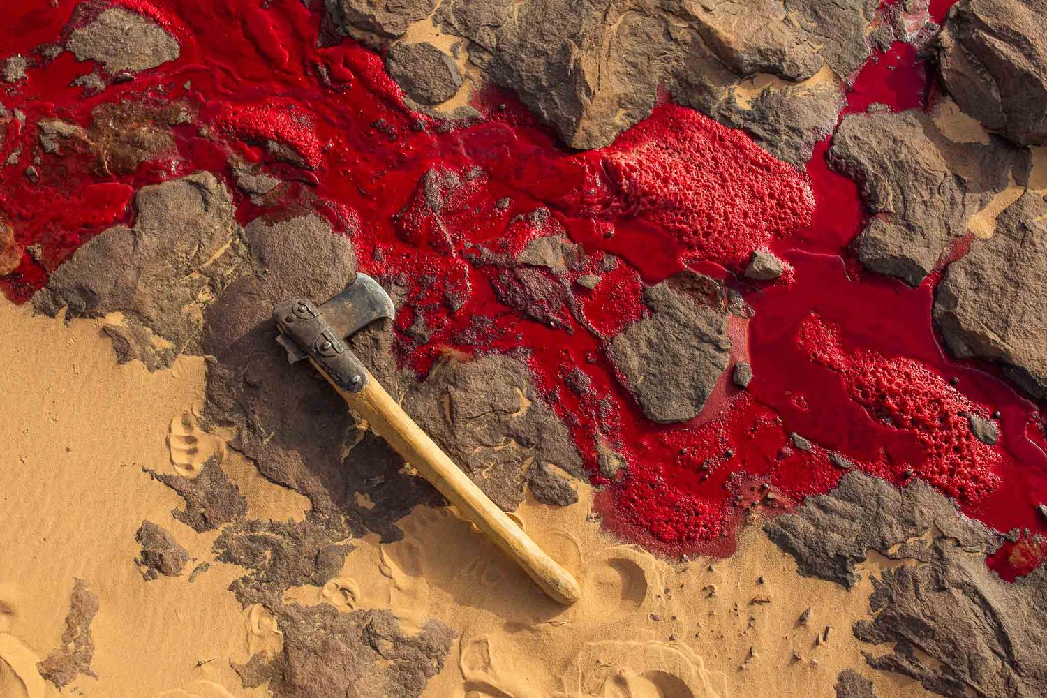 Vibrant red mineral formations spreading across desert rock surface.