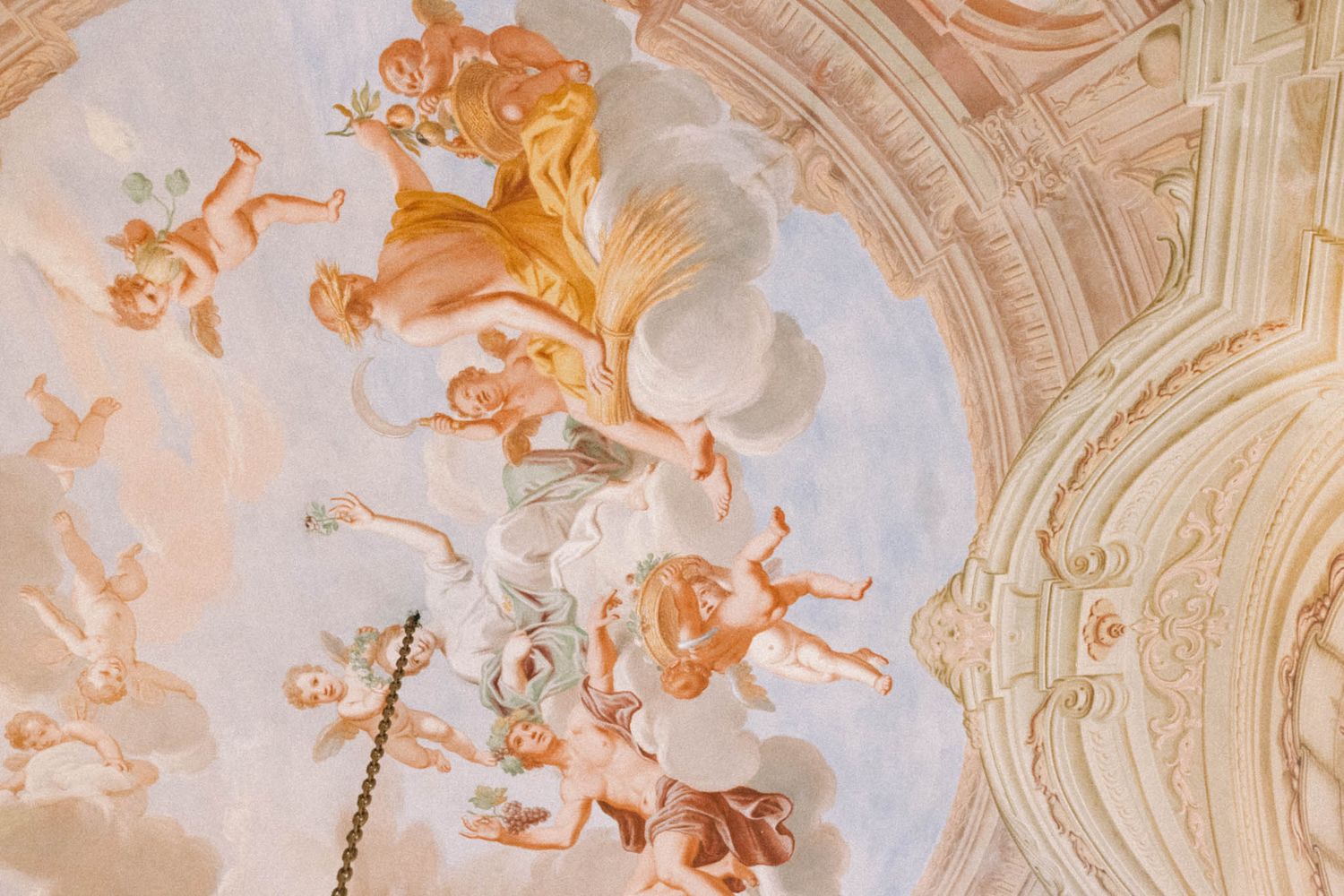 Ornate baroque ceiling fresco with cherubs and decorative elements painted in soft peach and cream colors.