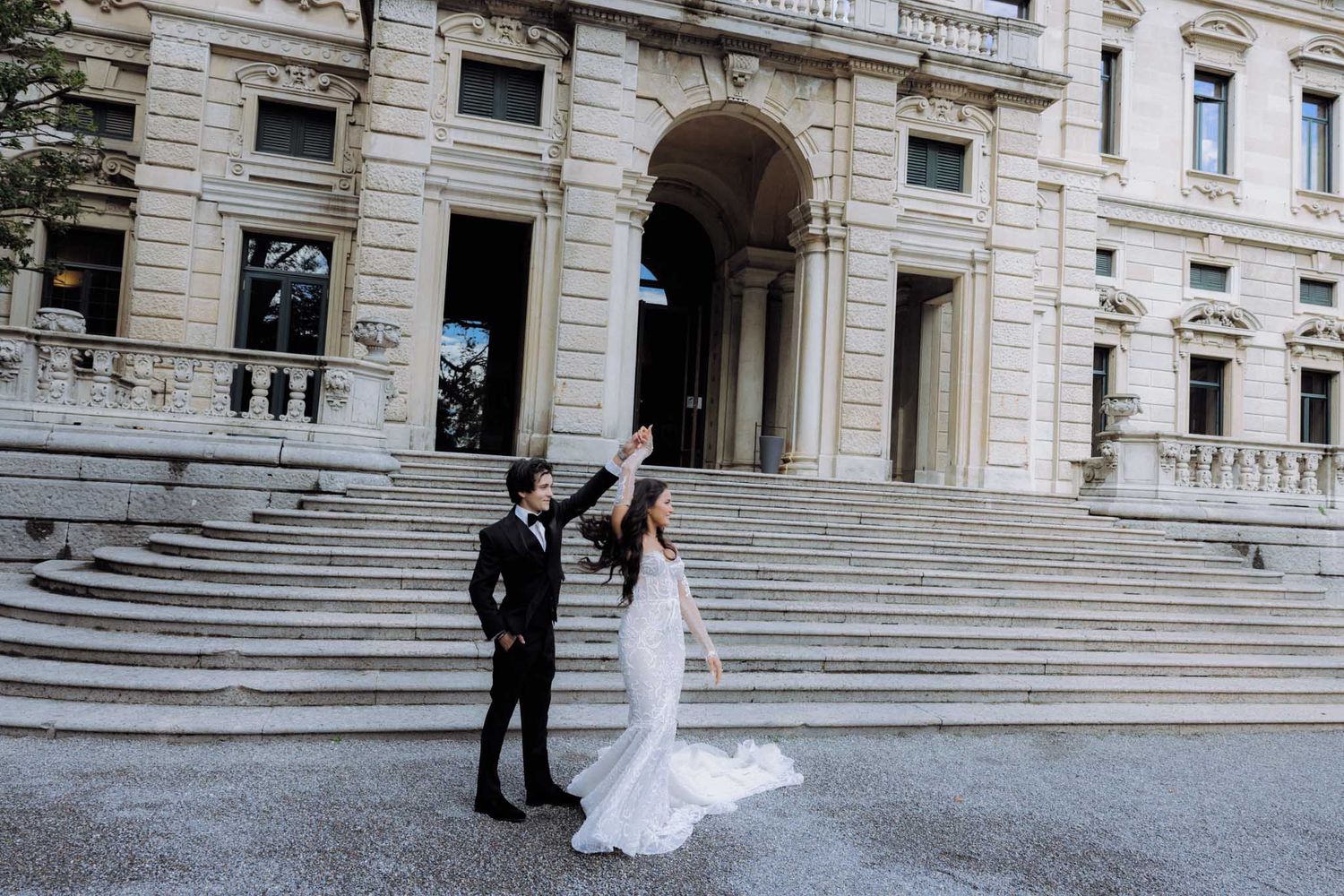 A panoramic view of a wedding couple and guests on grand stone steps of a historic building.