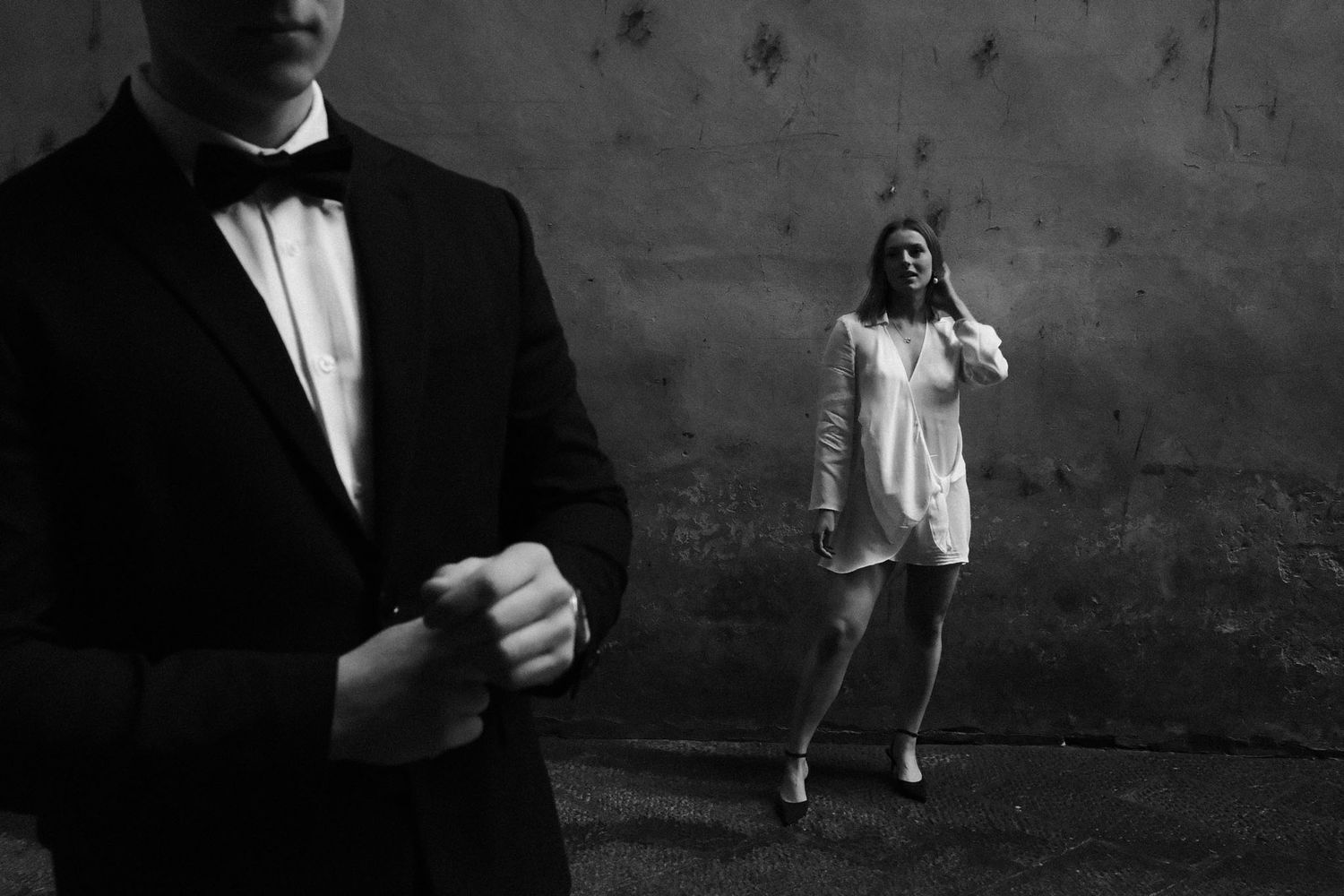 A dramatic black and white photo series showing a person walking through shadows and light against a dark wall.