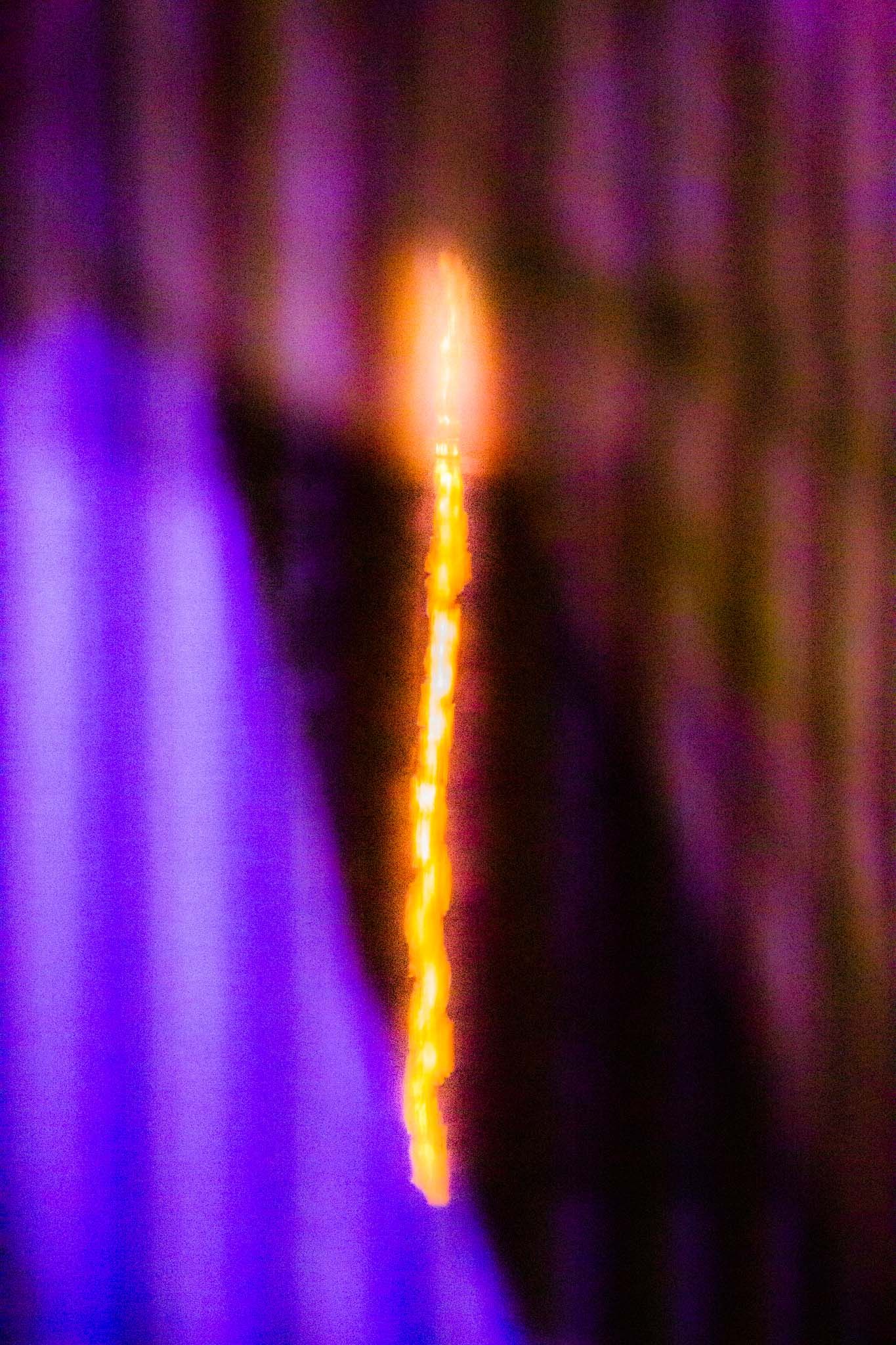A sequence of glowing orange light streaks against a purple background creates an abstract pattern of vertical lines.