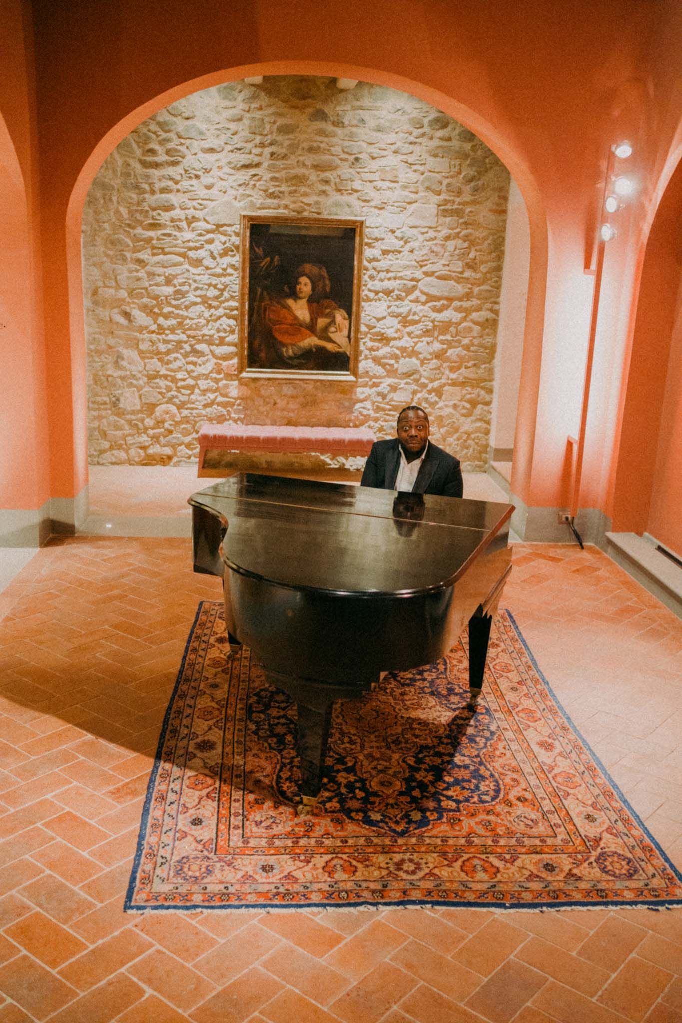 A vintage round table sits atop an ornate oriental rug in a room with stone walls and classic artwork.