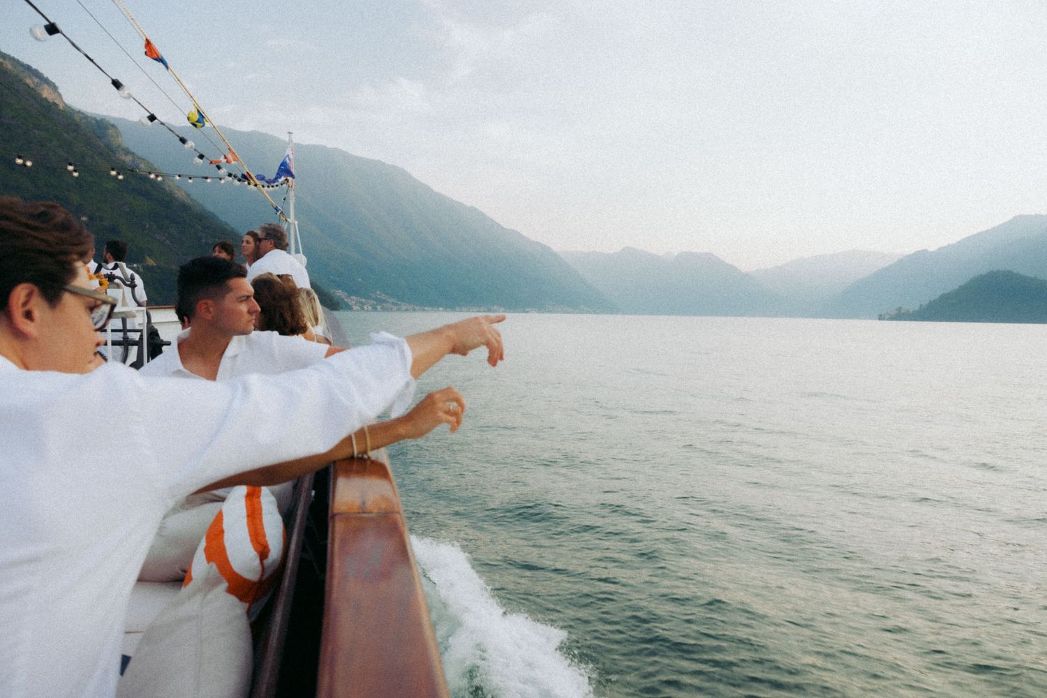 Passengers enjoying a boat ride on Lake Como with mountains and lakeside villas in the background.