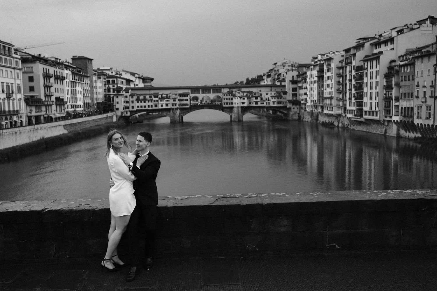Black and white photographs of a couple posing along a canal in Venice with historic buildings in the background.