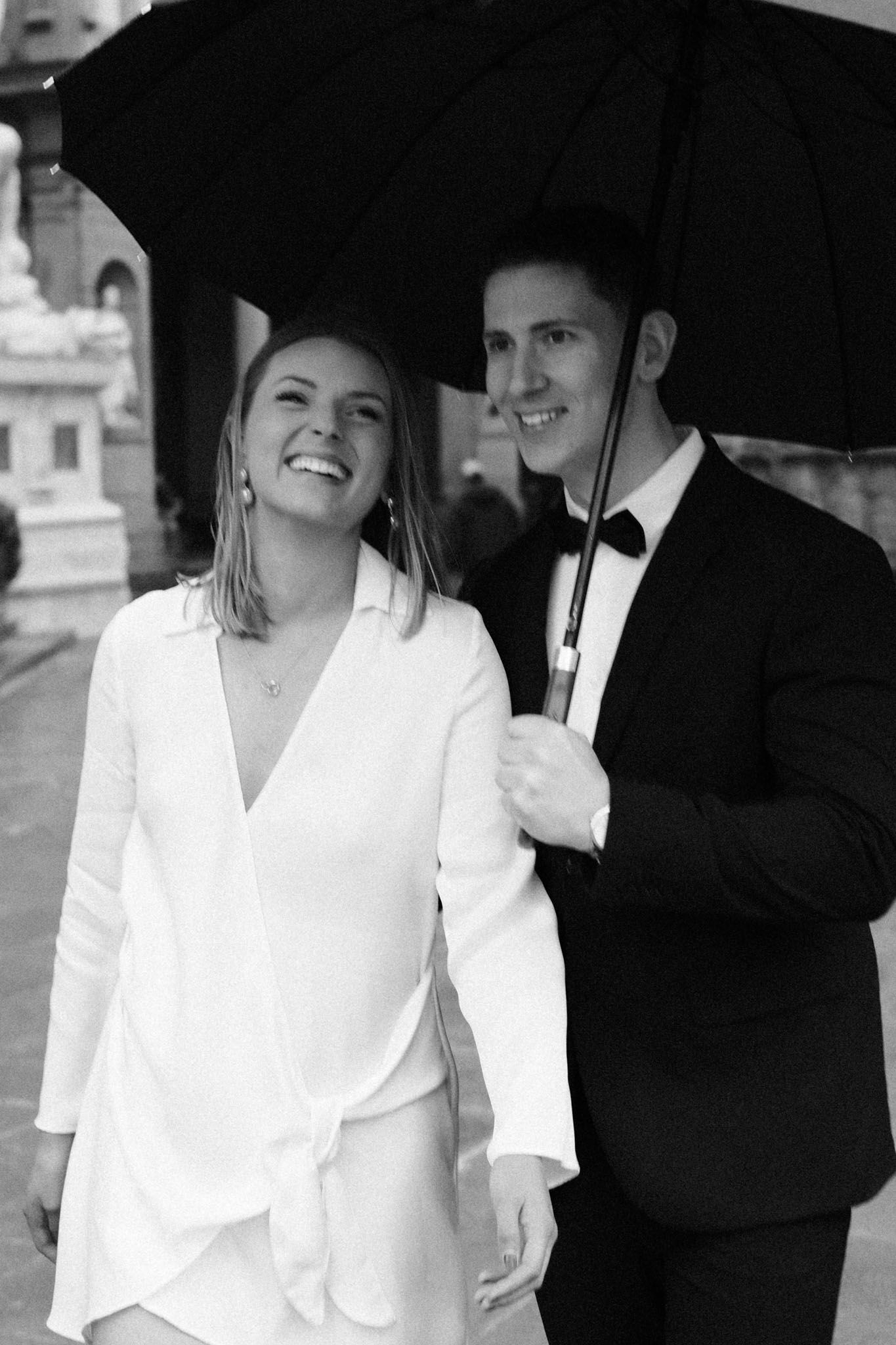 A couple shares an umbrella and laughs together in a series of black and white romantic photographs.