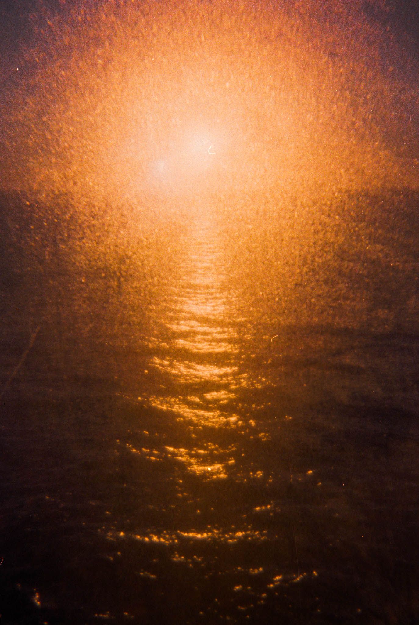Panoramic view of a golden sunset over rippling ocean waters creating a dramatic orange glow across the horizon.