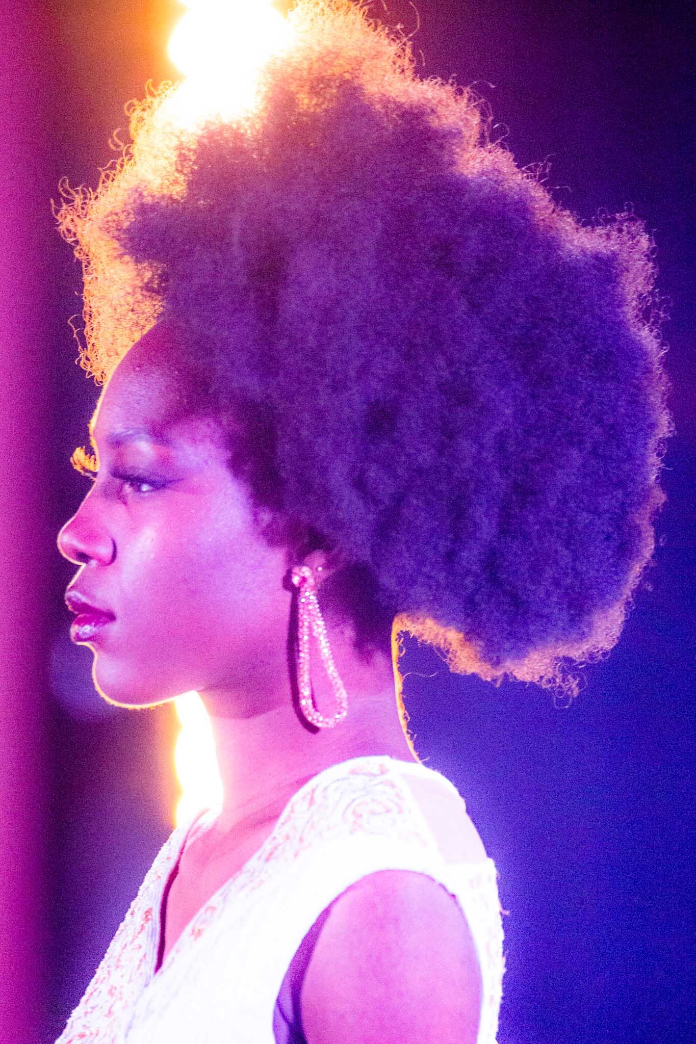 Artistic portrait series showing a silhouette with natural hair against vibrant purple and orange lighting.