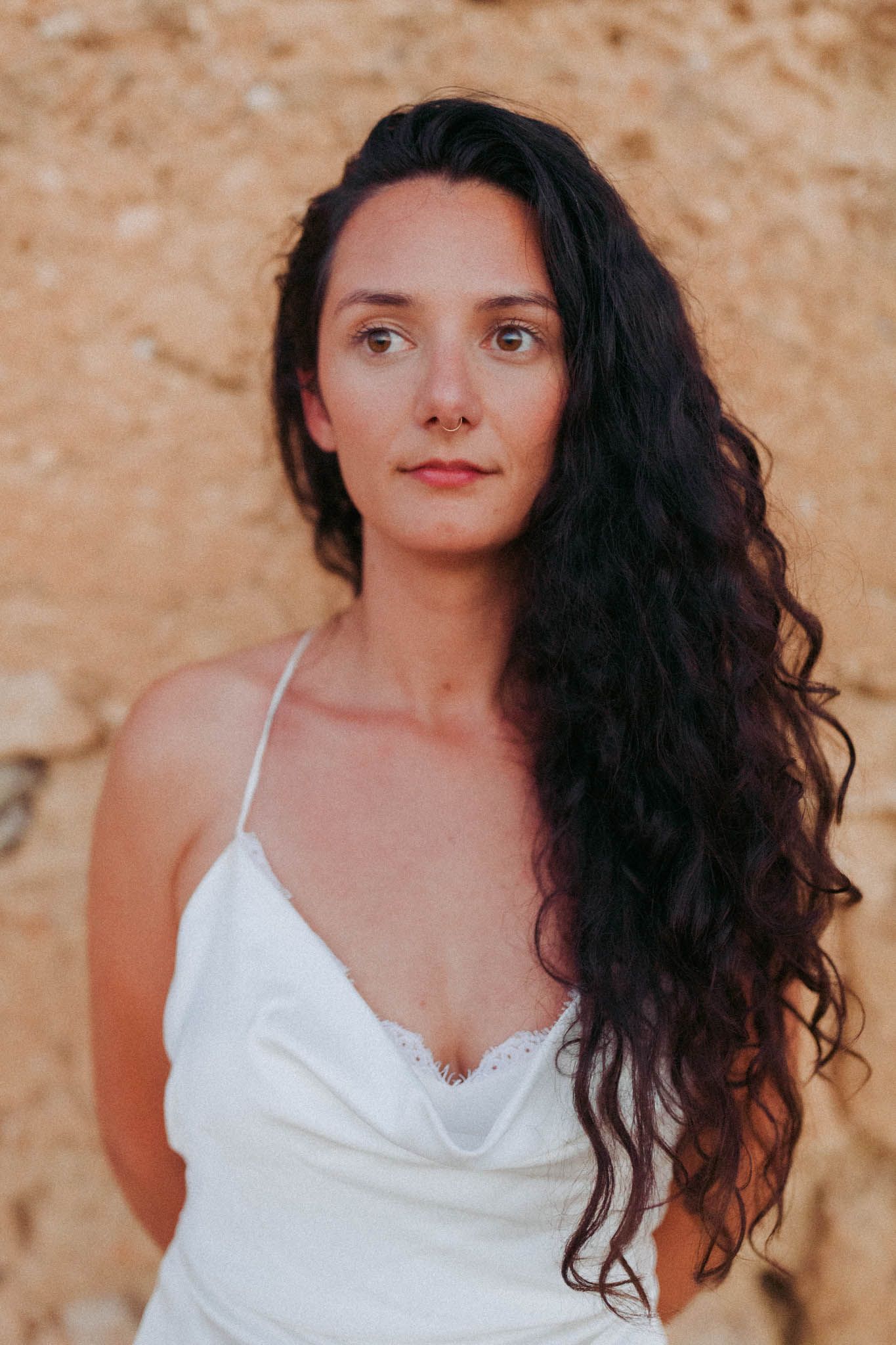 A series of portraits featuring dark curly hair and white clothing against an earthy brown backdrop.
