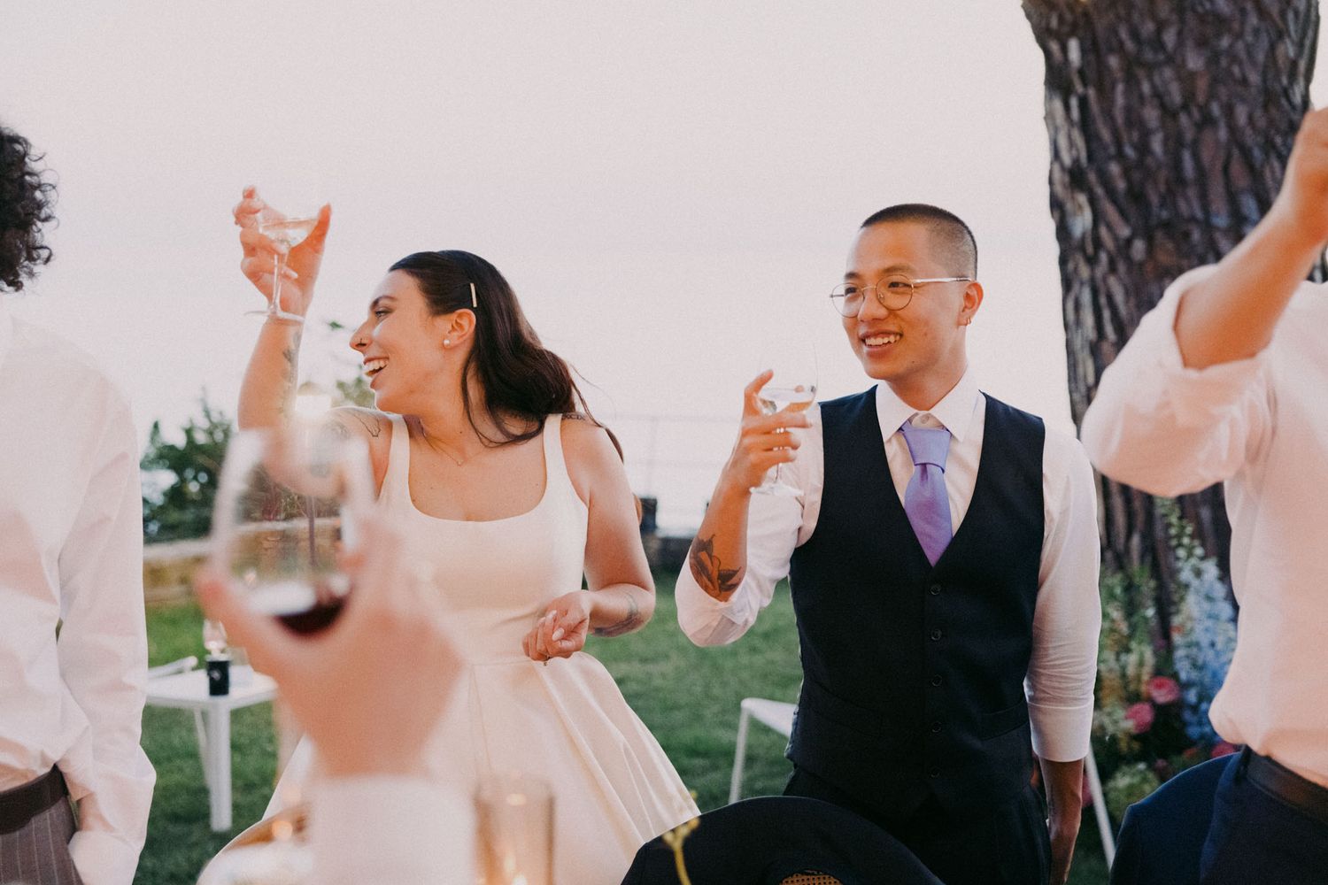 A romantic outdoor wedding celebration with guests dancing and mingling during golden hour at a garden reception.