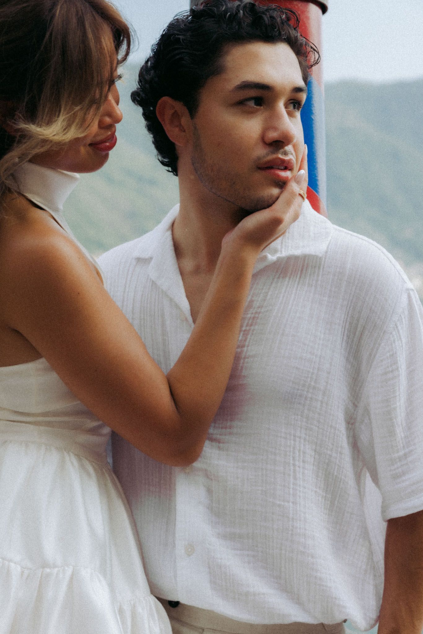 A tender moment between two people in white clothing against a soft blurred background.