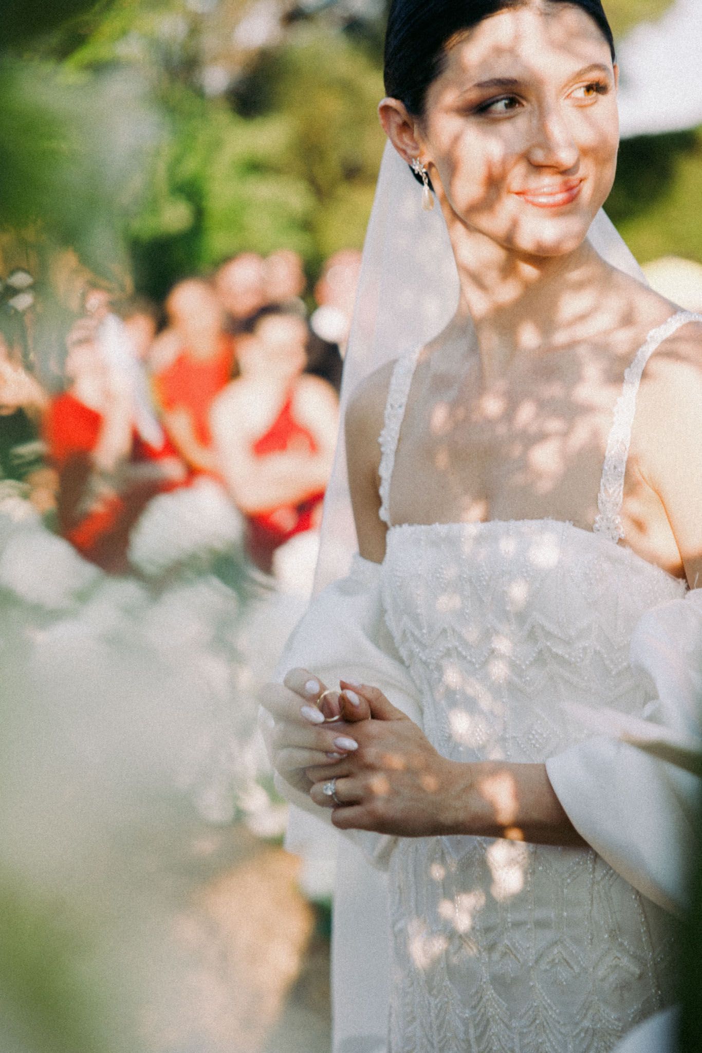 Sunlight filters through trees creating dappled light effects on a white lace wedding dress.