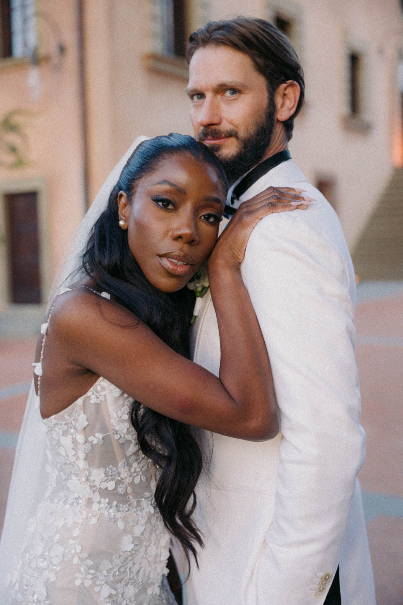A romantic wedding couple embraces in a series of intimate portraits against a soft blush-colored wall.