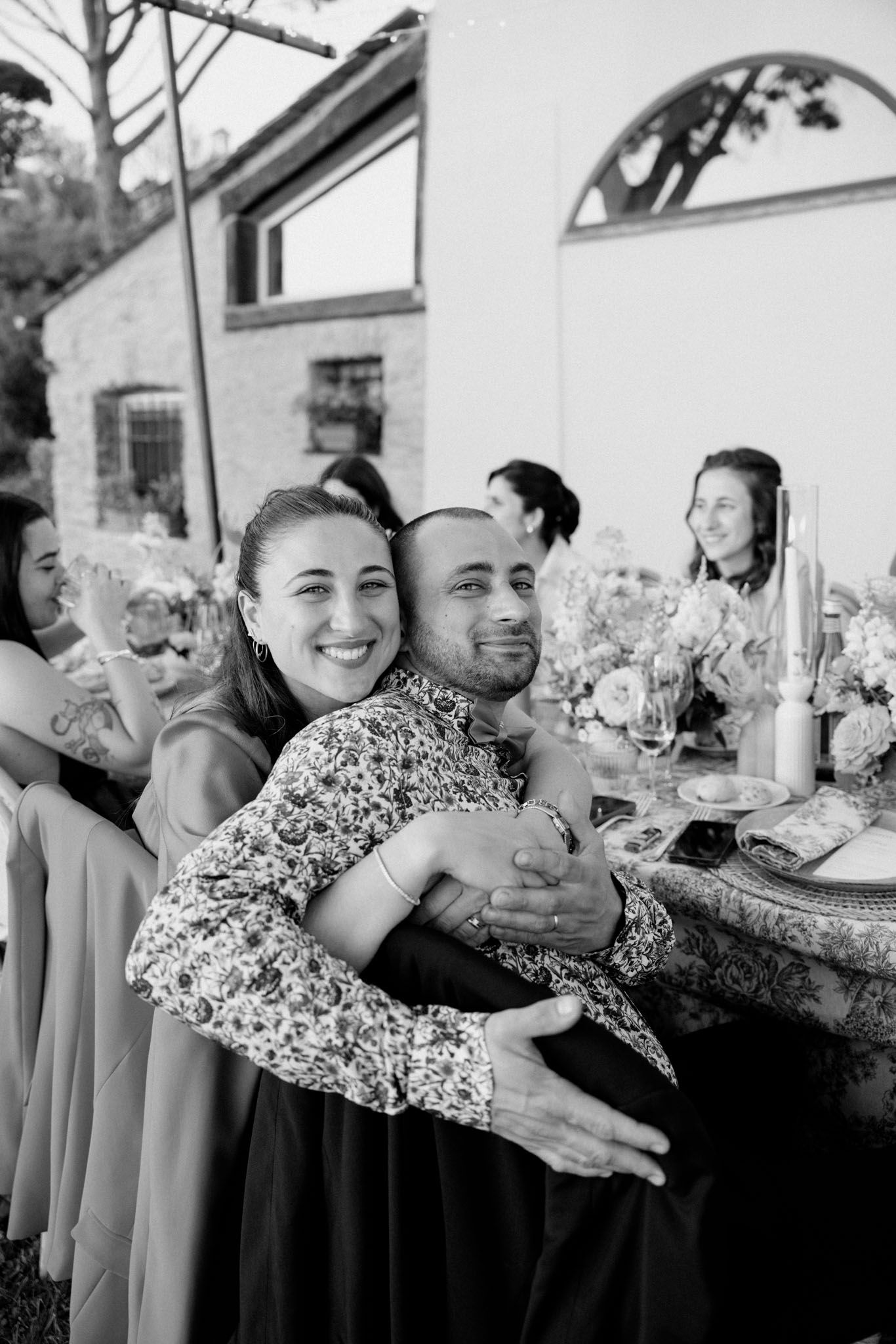 A group of bridesmaids in matching gray dresses pose together in a candid moment at a wedding celebration.