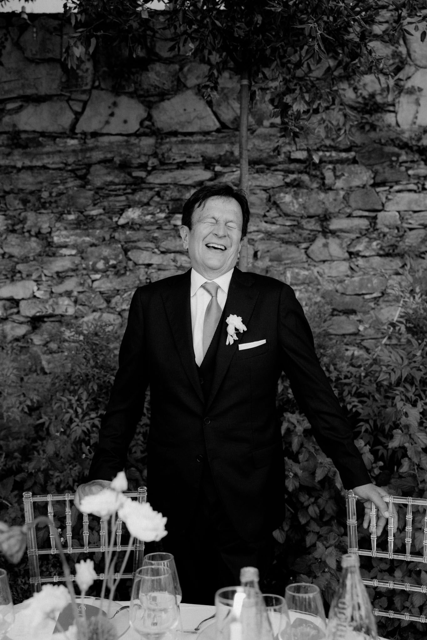 Black and white photo series showing moments of laughter and joy at an elegant outdoor wedding reception.