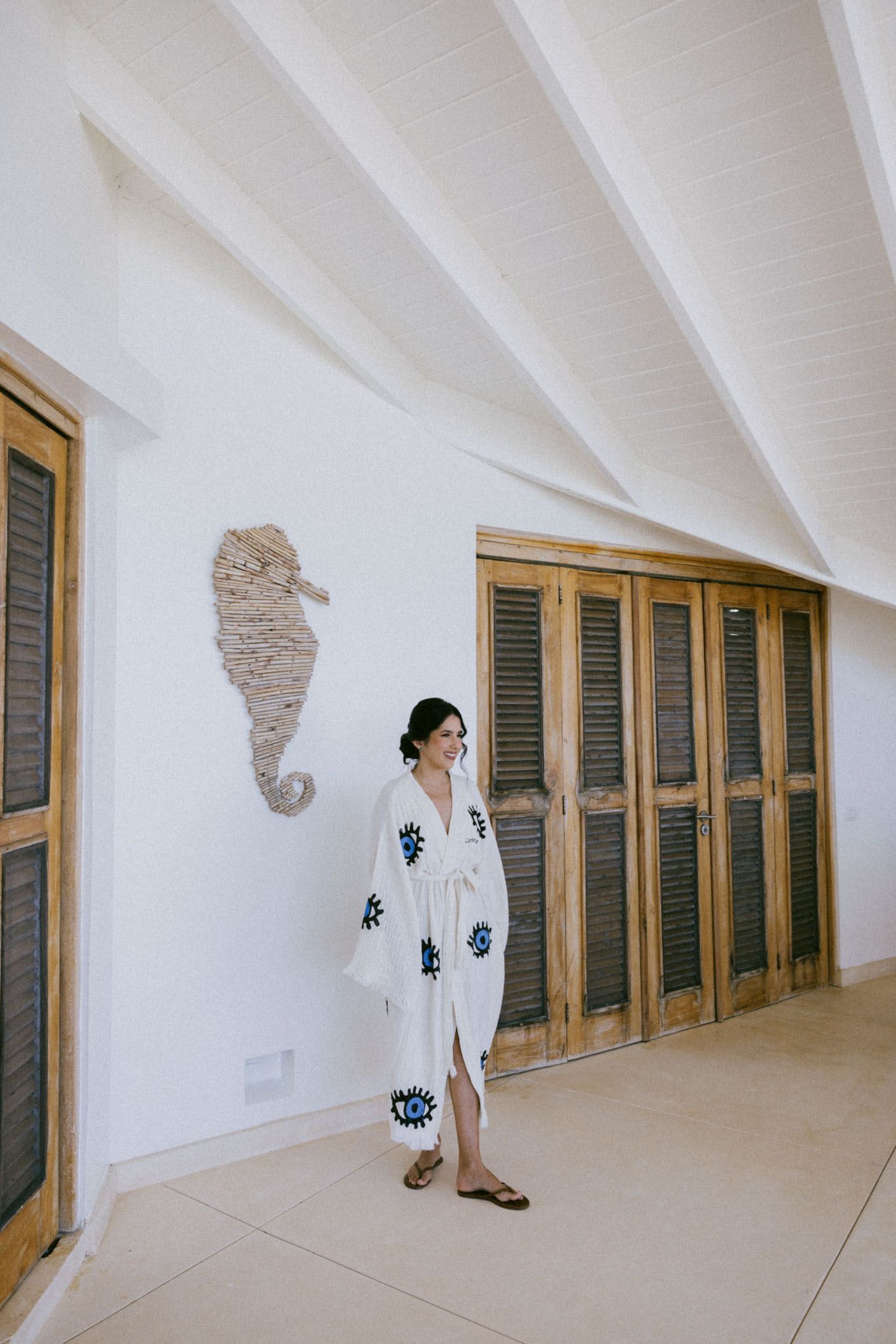 Three sequential photos show a figure in white against a minimalist hallway with green shuttered doors and stone wall accents.