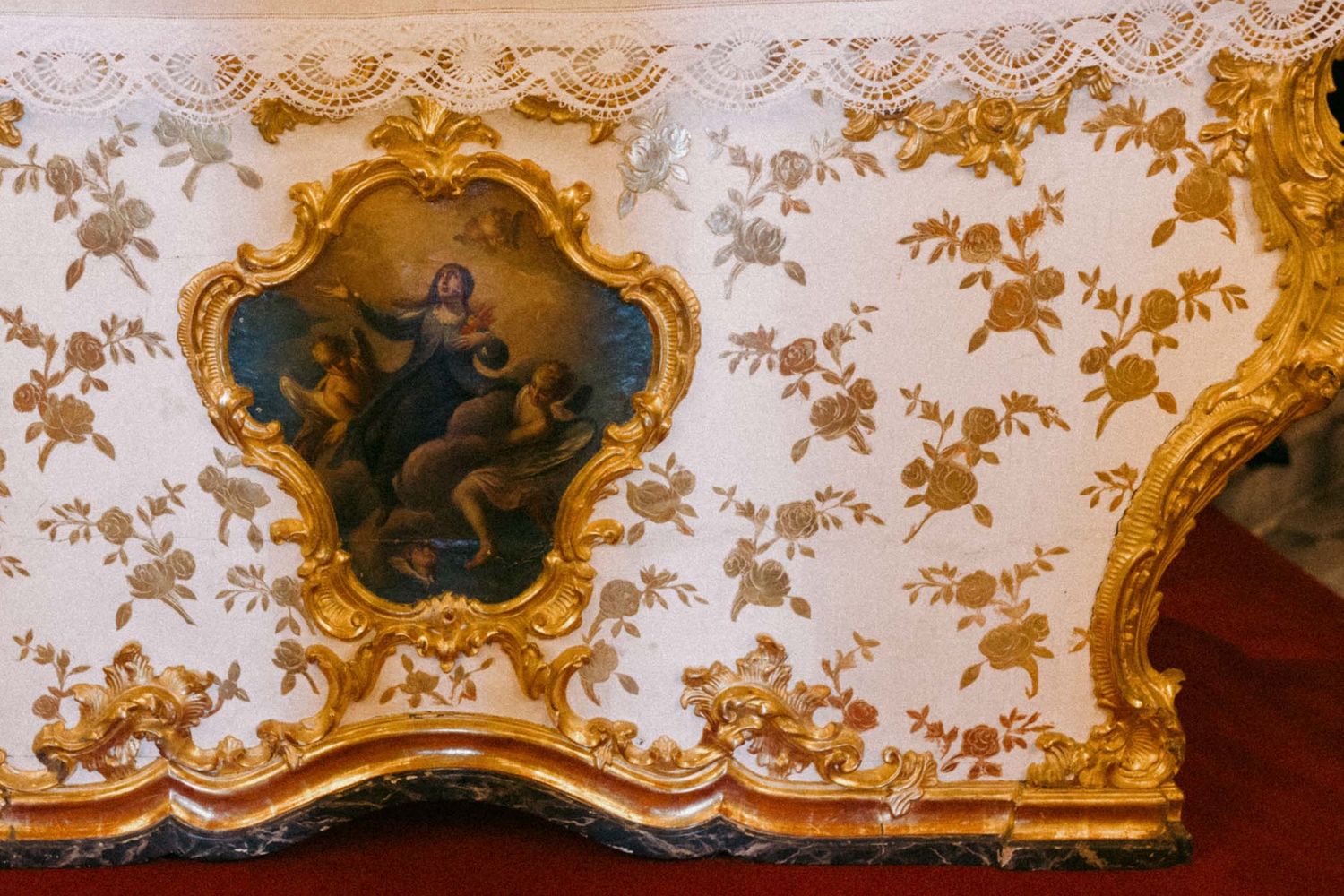 Ornate baroque ceiling with gilded frames and painted religious frescoes in an opulent European palace interior.