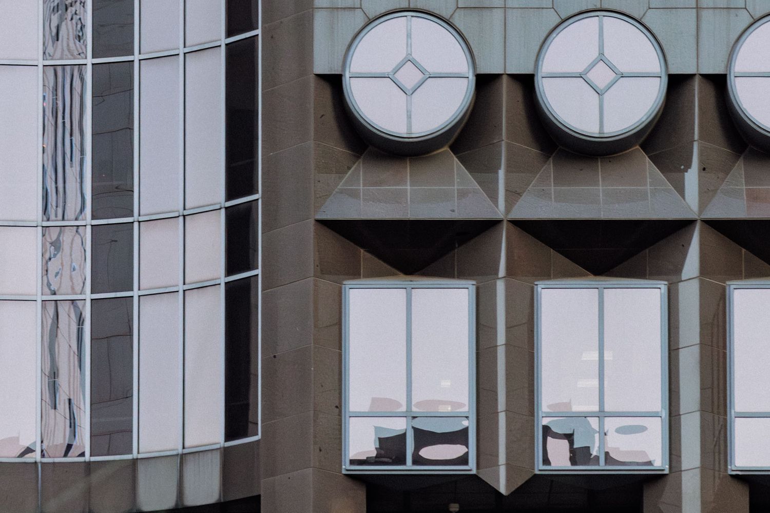 Modern office building exterior with large circular clock displays mounted on glass facade.