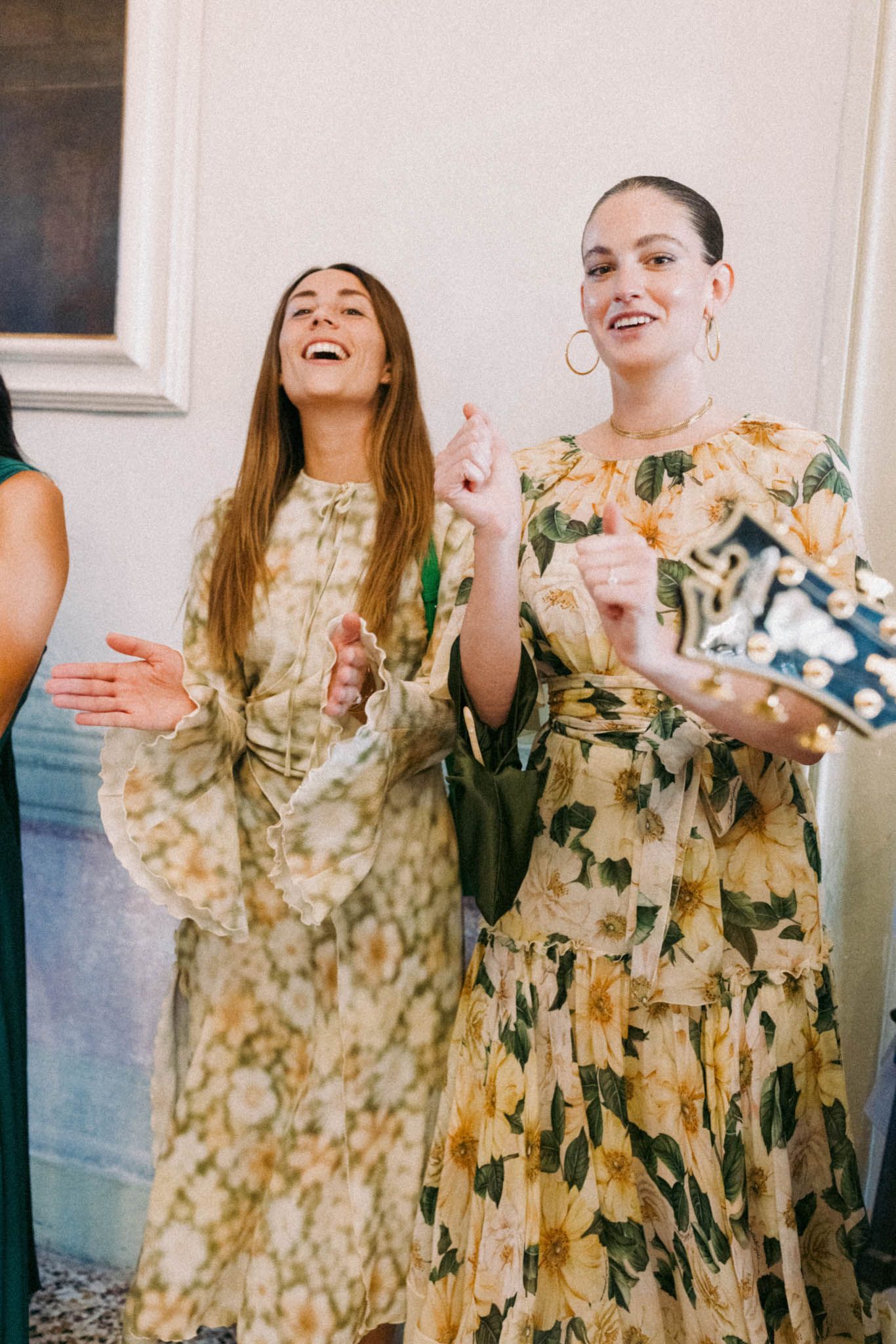 Group wearing matching floral print dresses share joyful laughter in a candid moment.