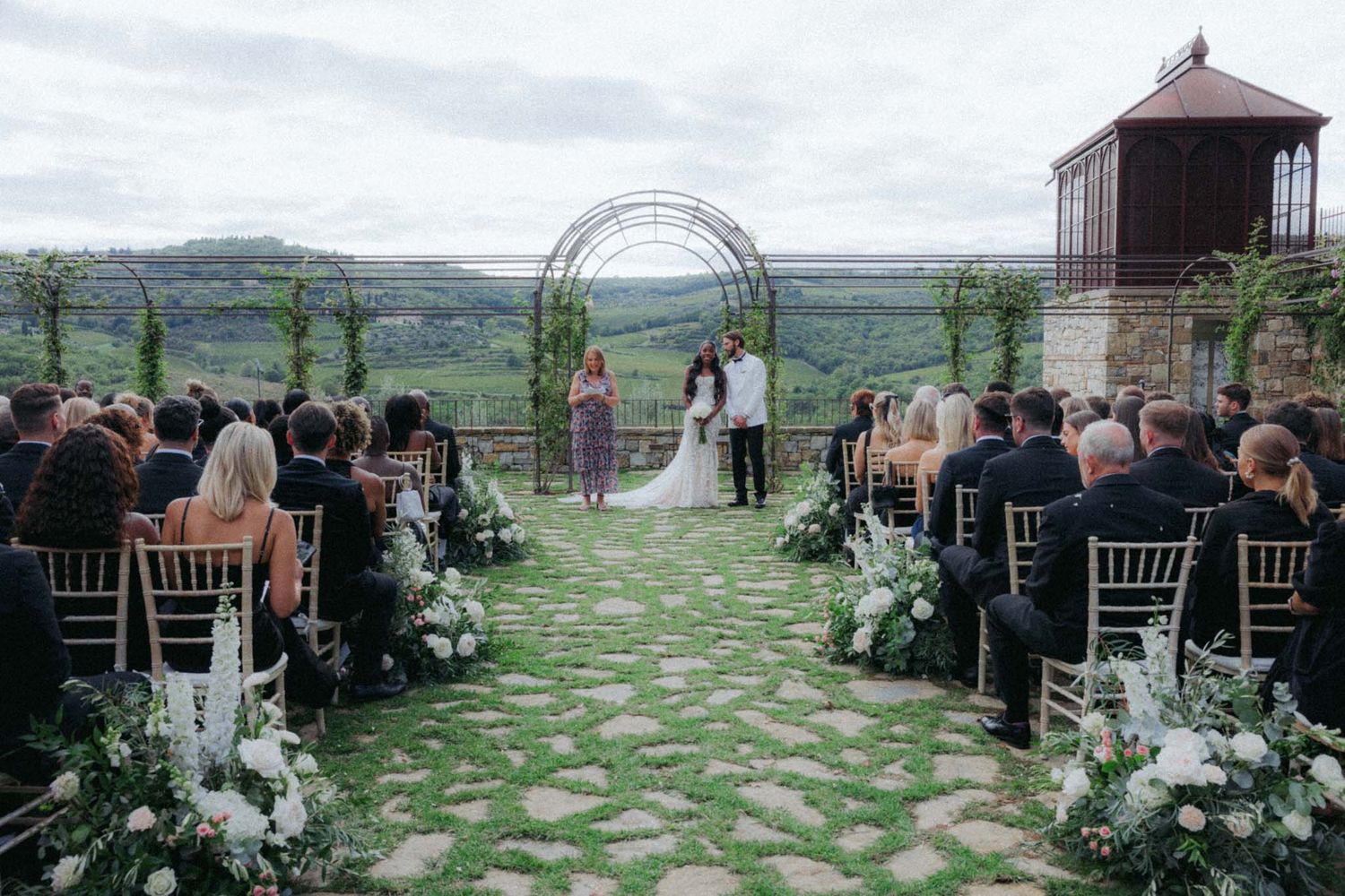 Outdoor wedding ceremony setup with chairs arranged on a grassy hilltop overlooking scenic mountain views.