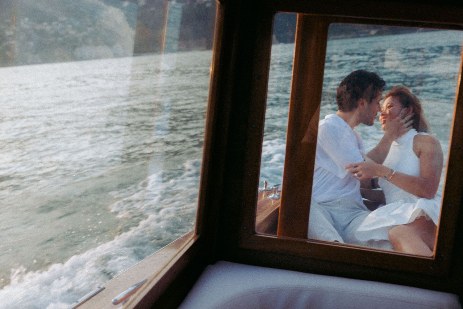 A couple shares an intimate moment together while sitting by a window overlooking the ocean.