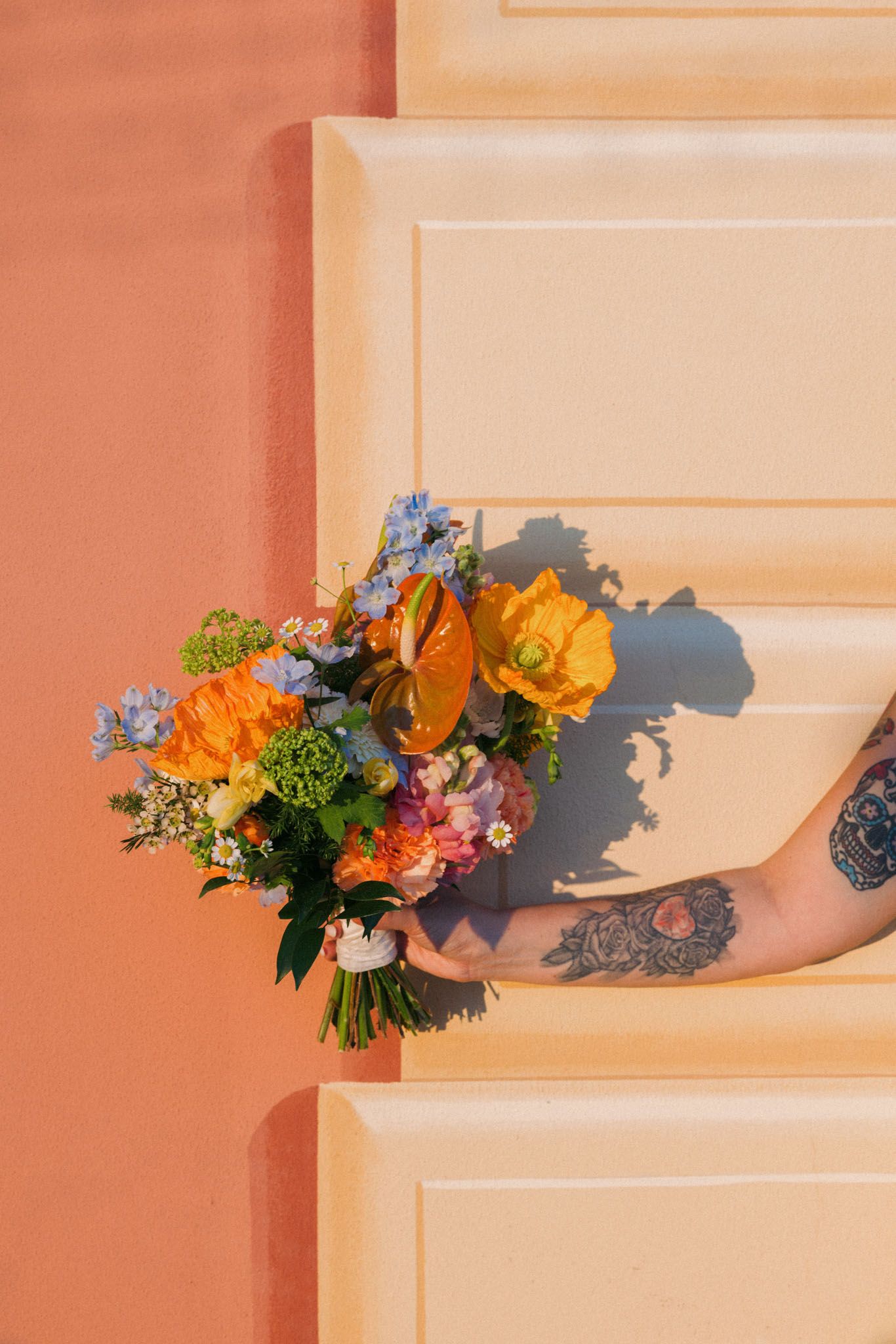 A colorful floral arrangement casts dramatic shadows on a peach-colored wall in a progressive time-lapse sequence.