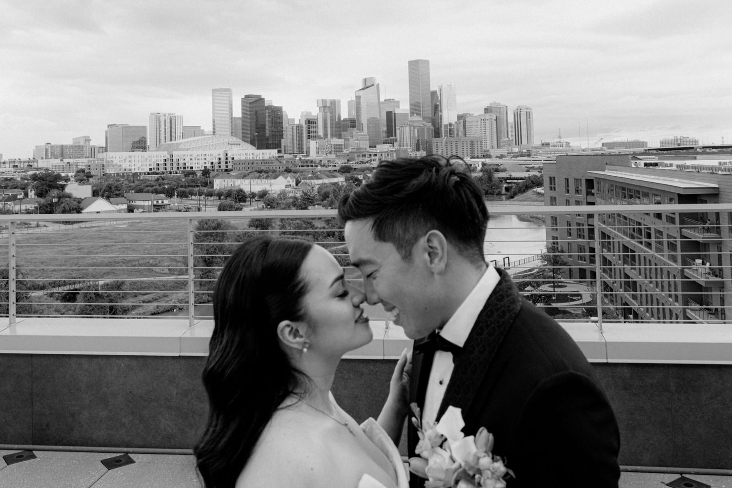 A couple shares a romantic kiss with the Minneapolis skyline visible in the background during a rooftop photo session.