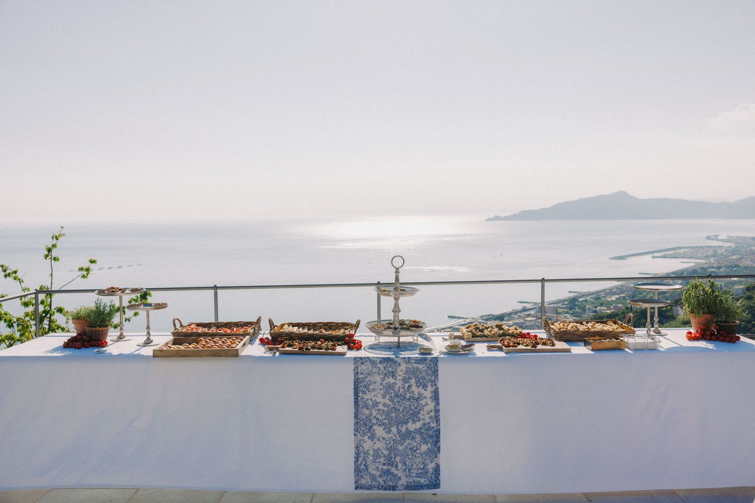 Elegant wedding reception table setup overlooking a coastal Mediterranean landscape with white decor and ocean views.