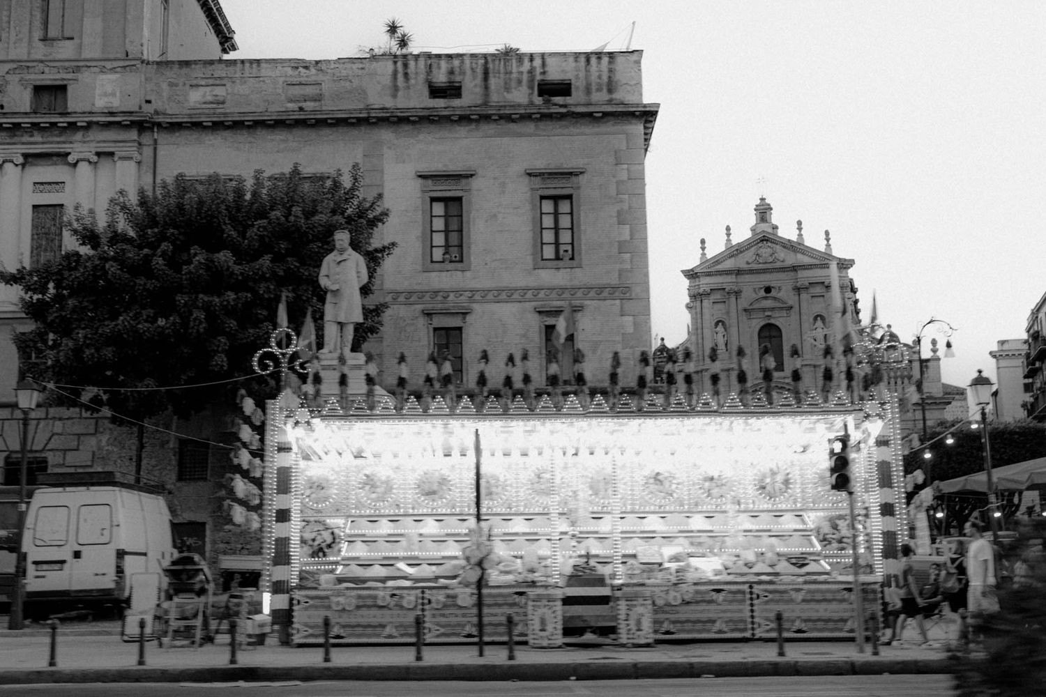 A black and white panoramic photograph shows a historic building facade with ornate architectural details and stone steps.