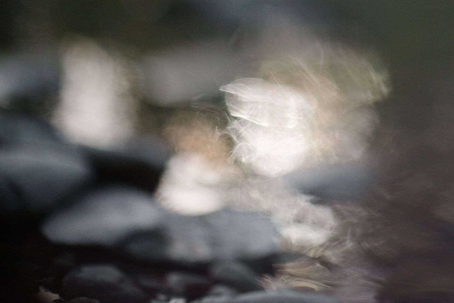 Abstract photograph of light reflecting on moving water, with soft blurred forms and luminous highlights