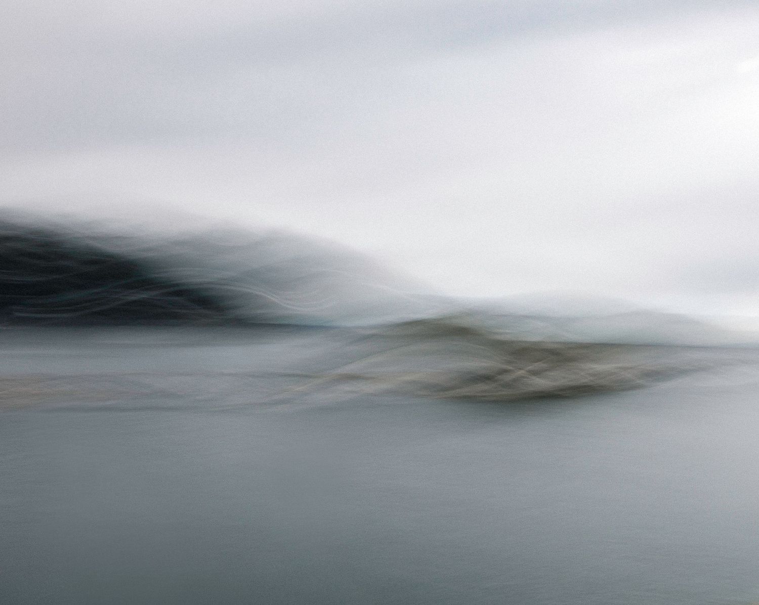 Abstract seascape photography with blurred motion of waves and misty gray atmosphere creates a moody minimalist composition.
