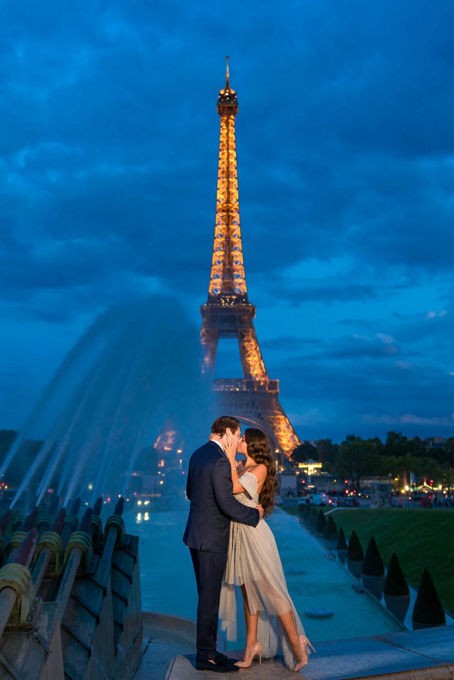 Couple romantique s’enlaçant près de la Tour Eiffel illuminée au crépuscule.